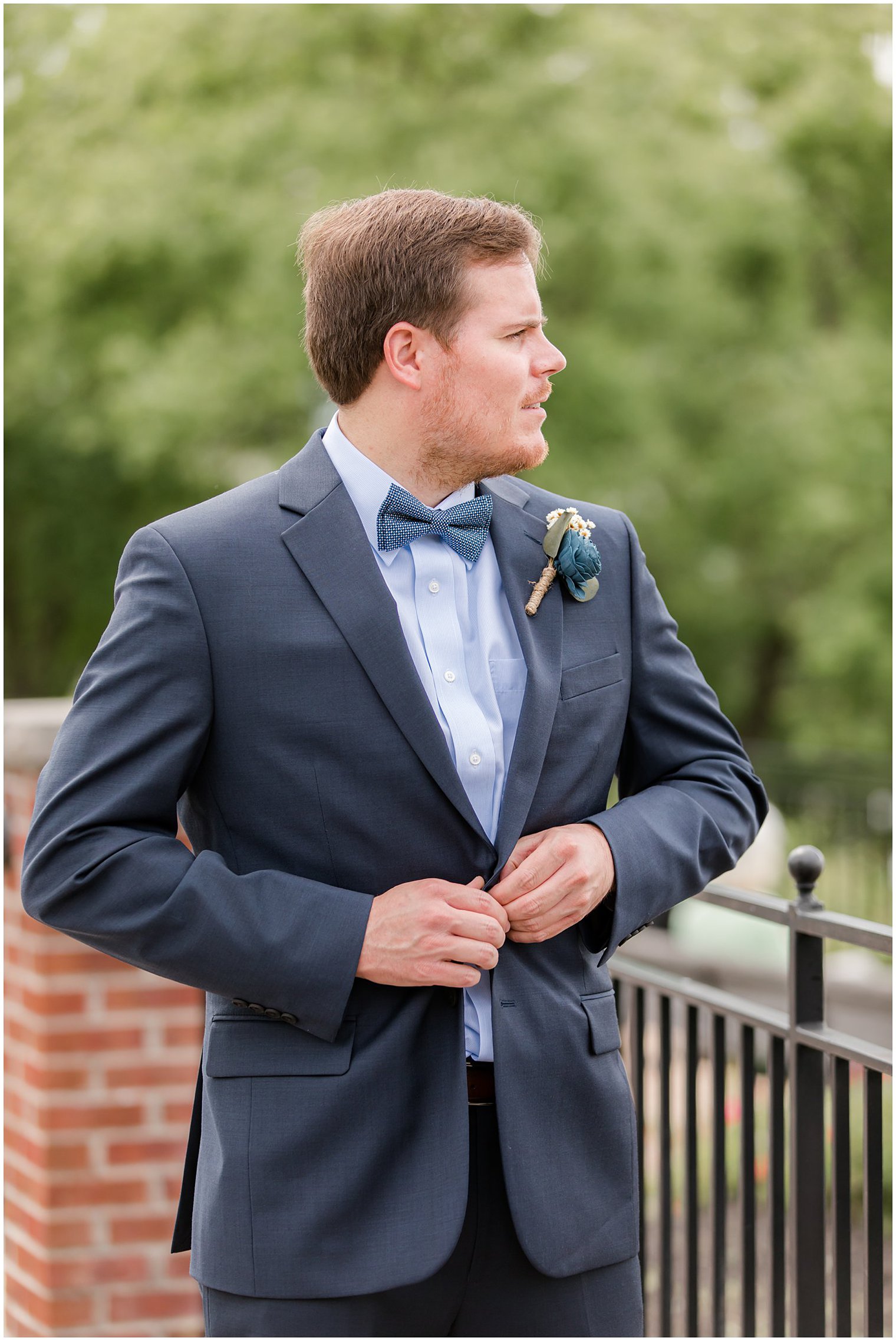 groom looks over shoulder while buttoning suit jacket 