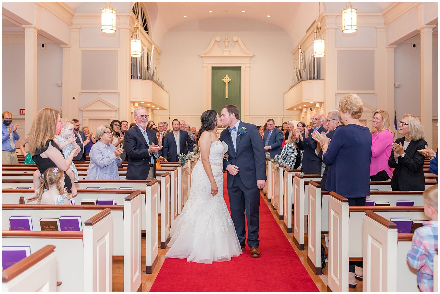 newlyweds kiss in aisle during traditional church wedding in Red Bank New Jersey 