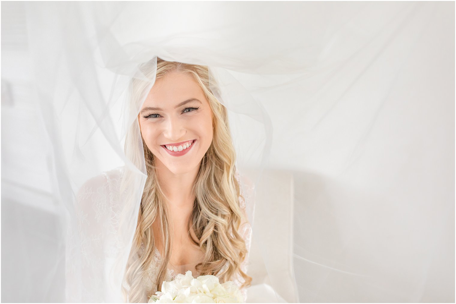 bride smiles from under veil during wedding prep portraits 