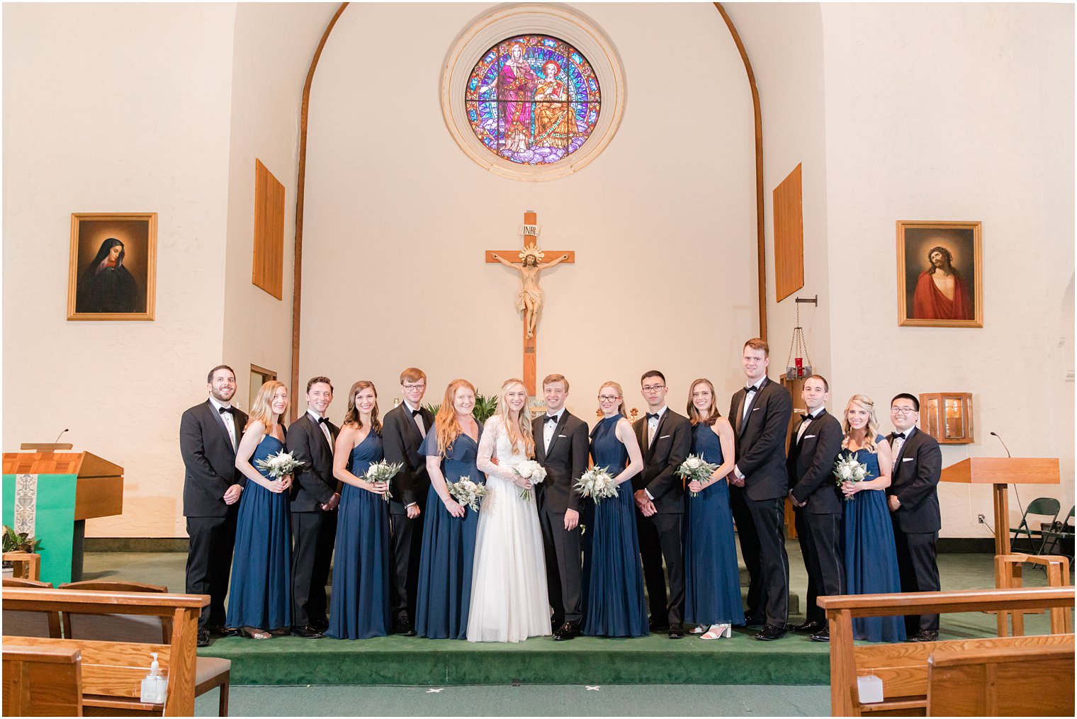 bridesmaids in navy blue dresses pose with bride and groom 