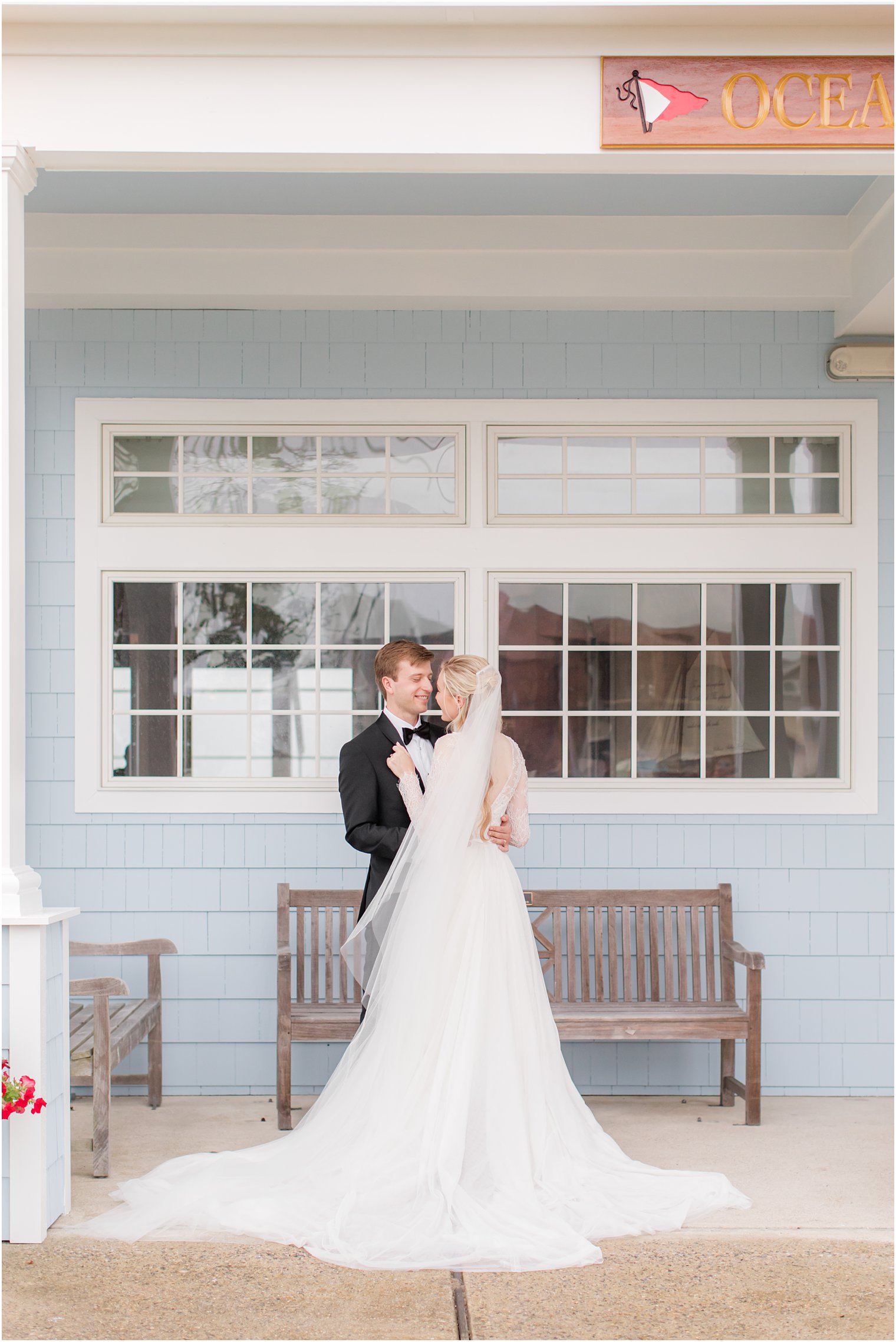 bride holds groom's lapels while standing under awning on rainy wedding day