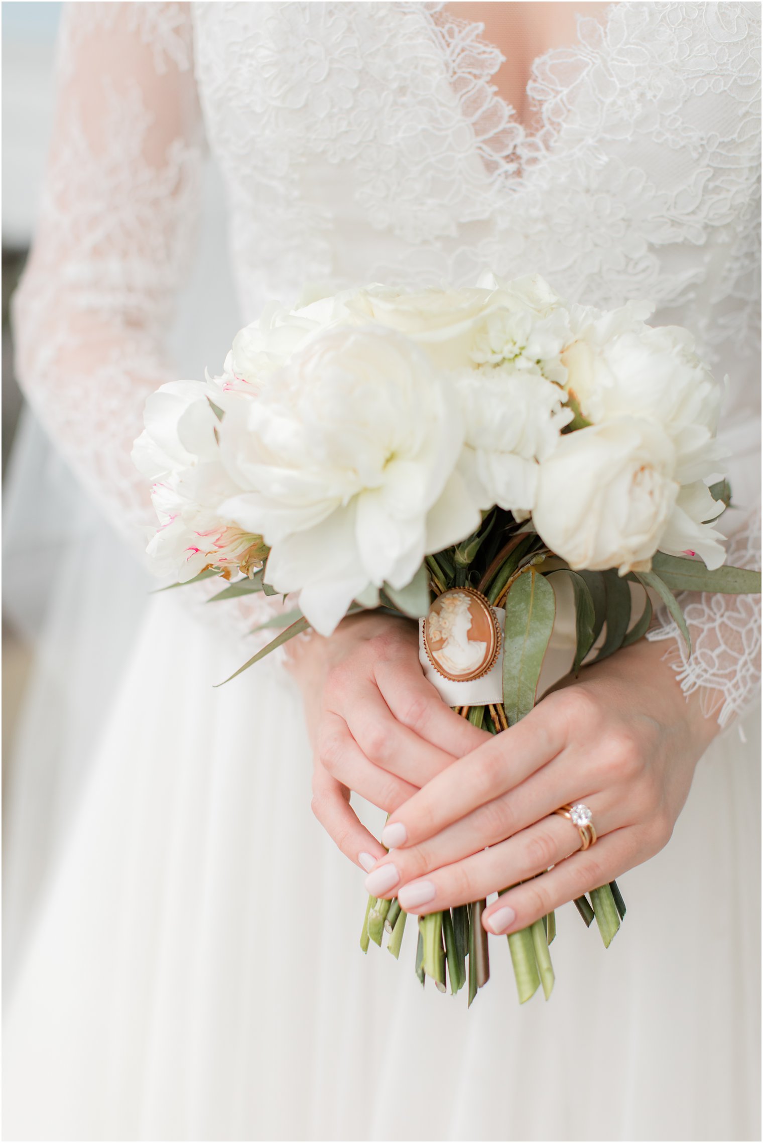 bride holds small bouquet of white flowers with brooch