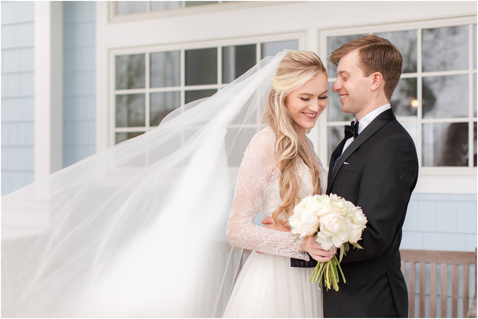 groom smiles at bride while she looks at bouquet in Ocean City NJ