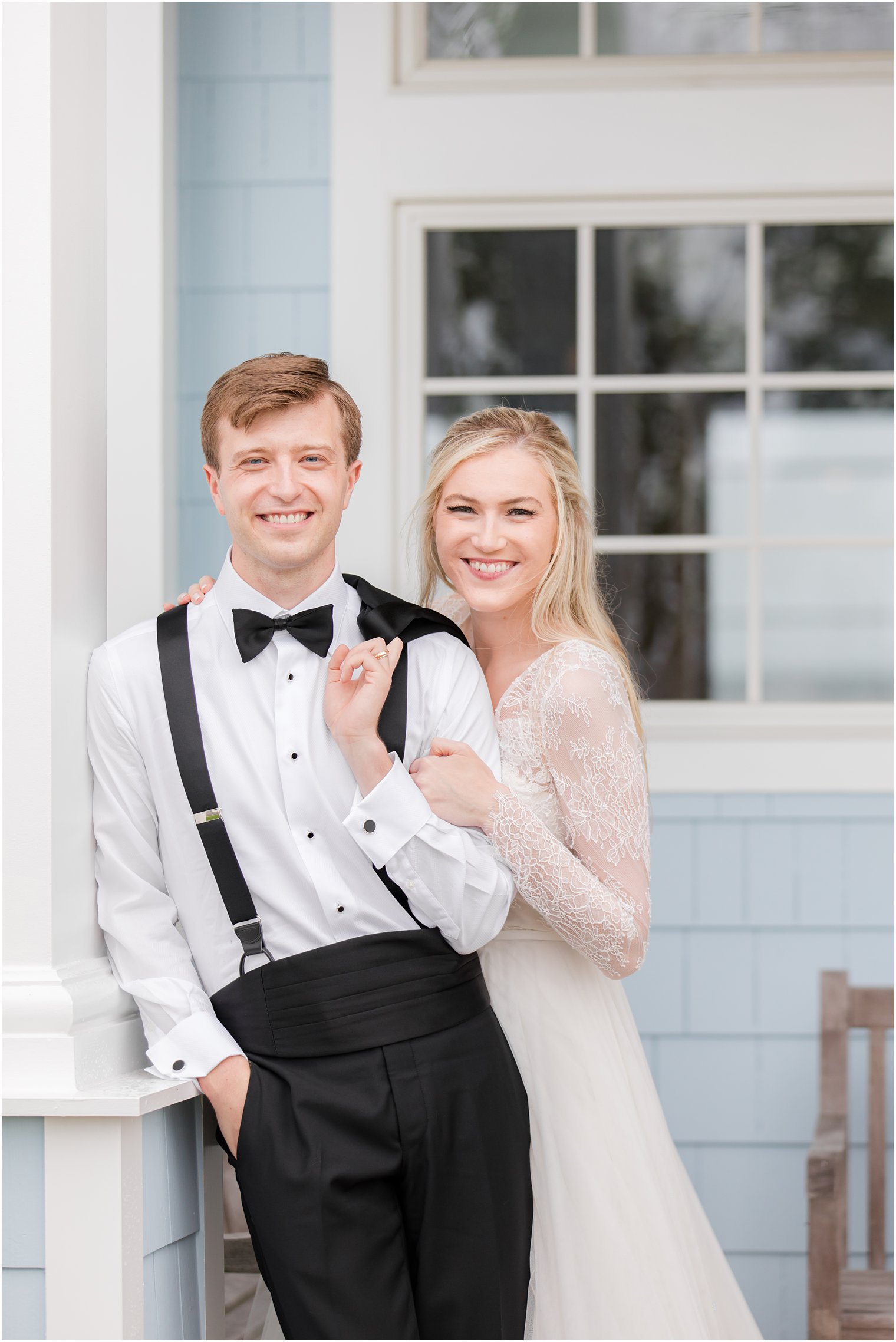 groom stands with jacket over shoulder with bride holding his arm