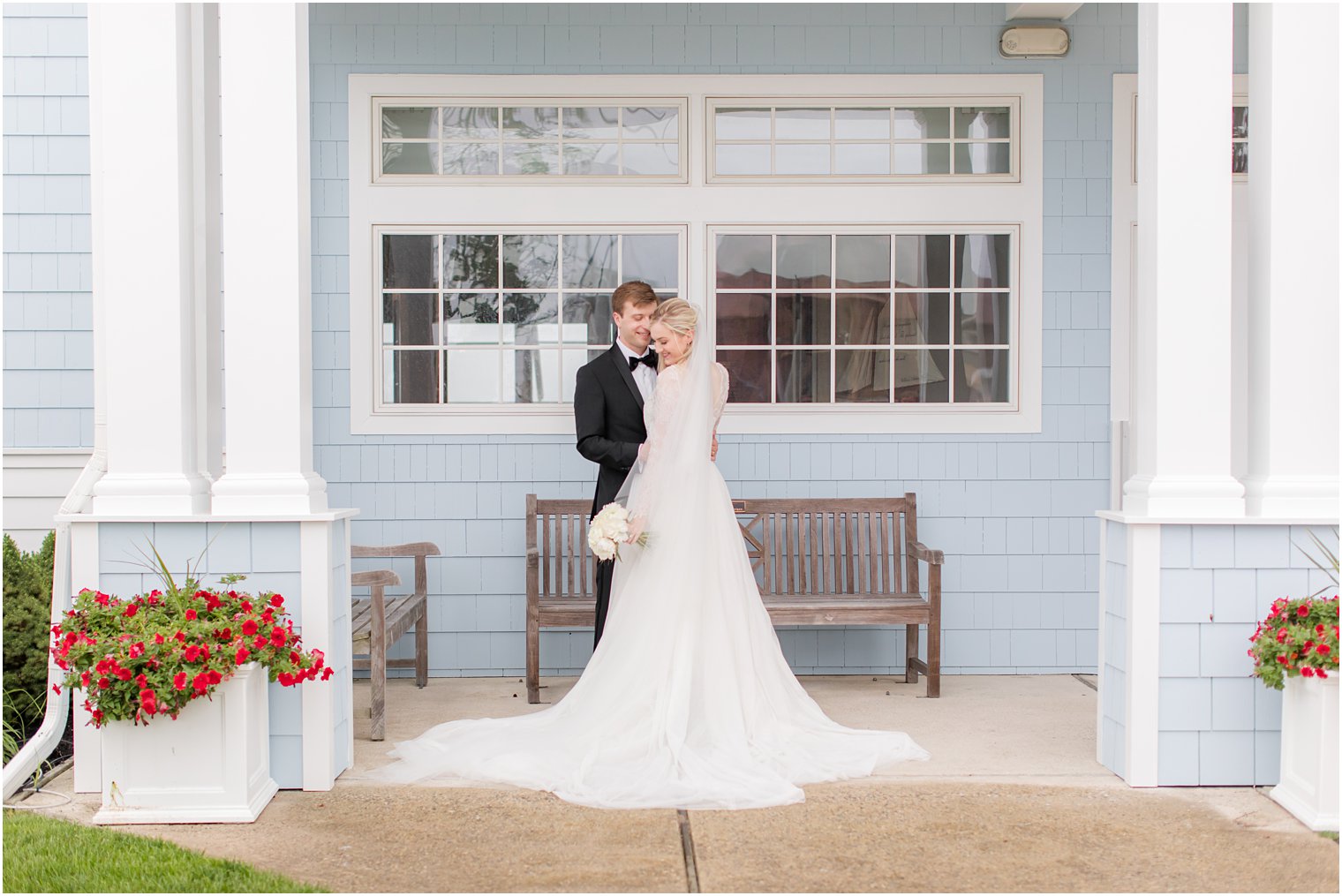 newlyweds pose together by blue wall at Ocean City Yacht Club