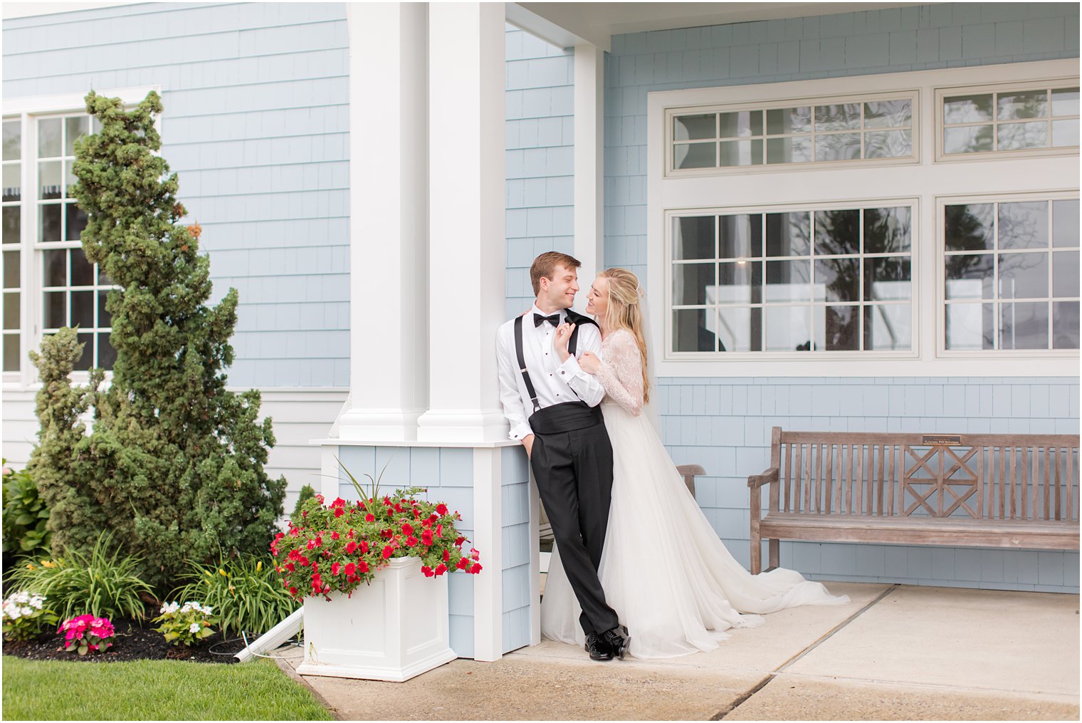 bride and groom lean against pole by blue wall at Ocean City Yacht Club