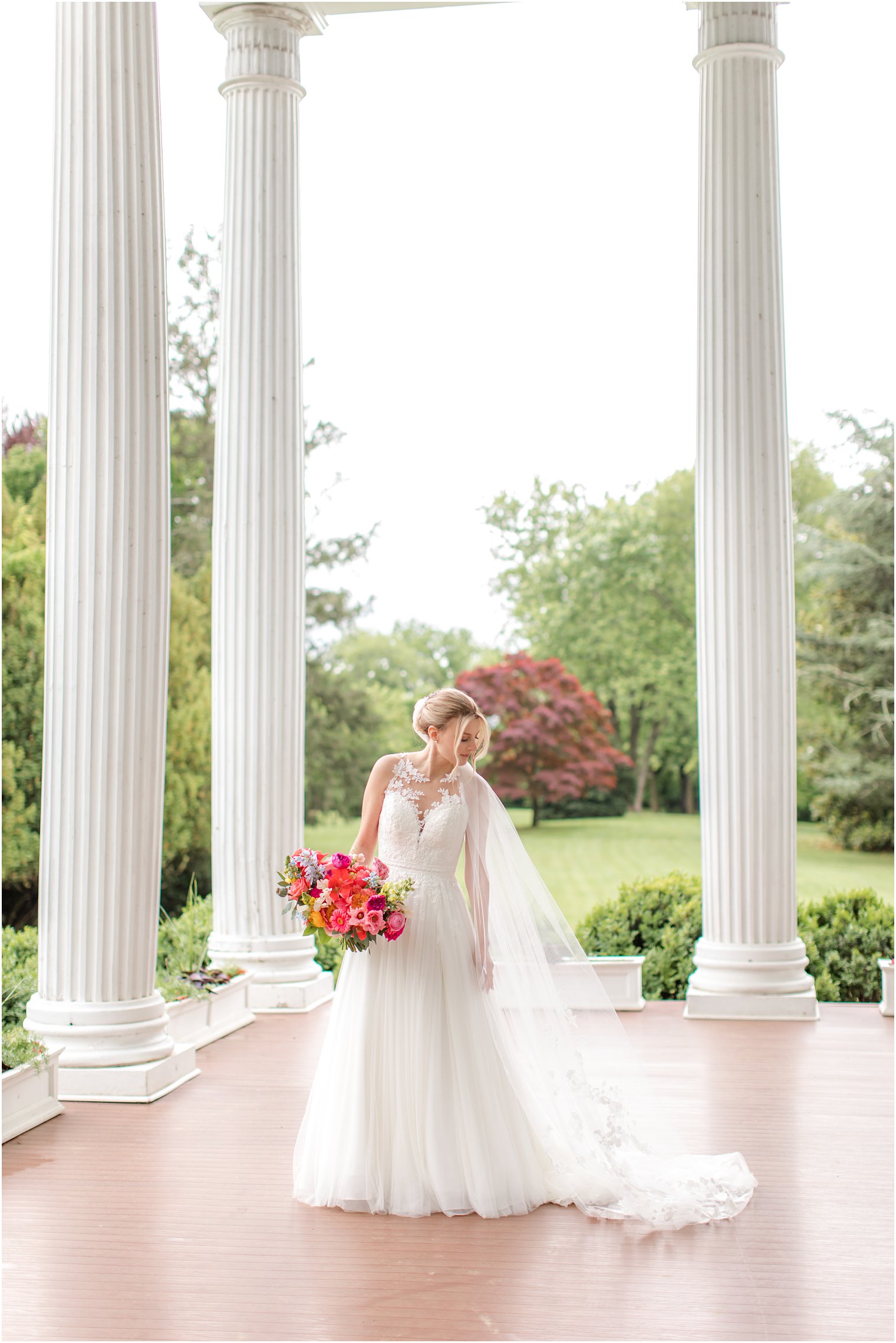 bride looks over shoulder at veil on veranda at Rosemont Manor