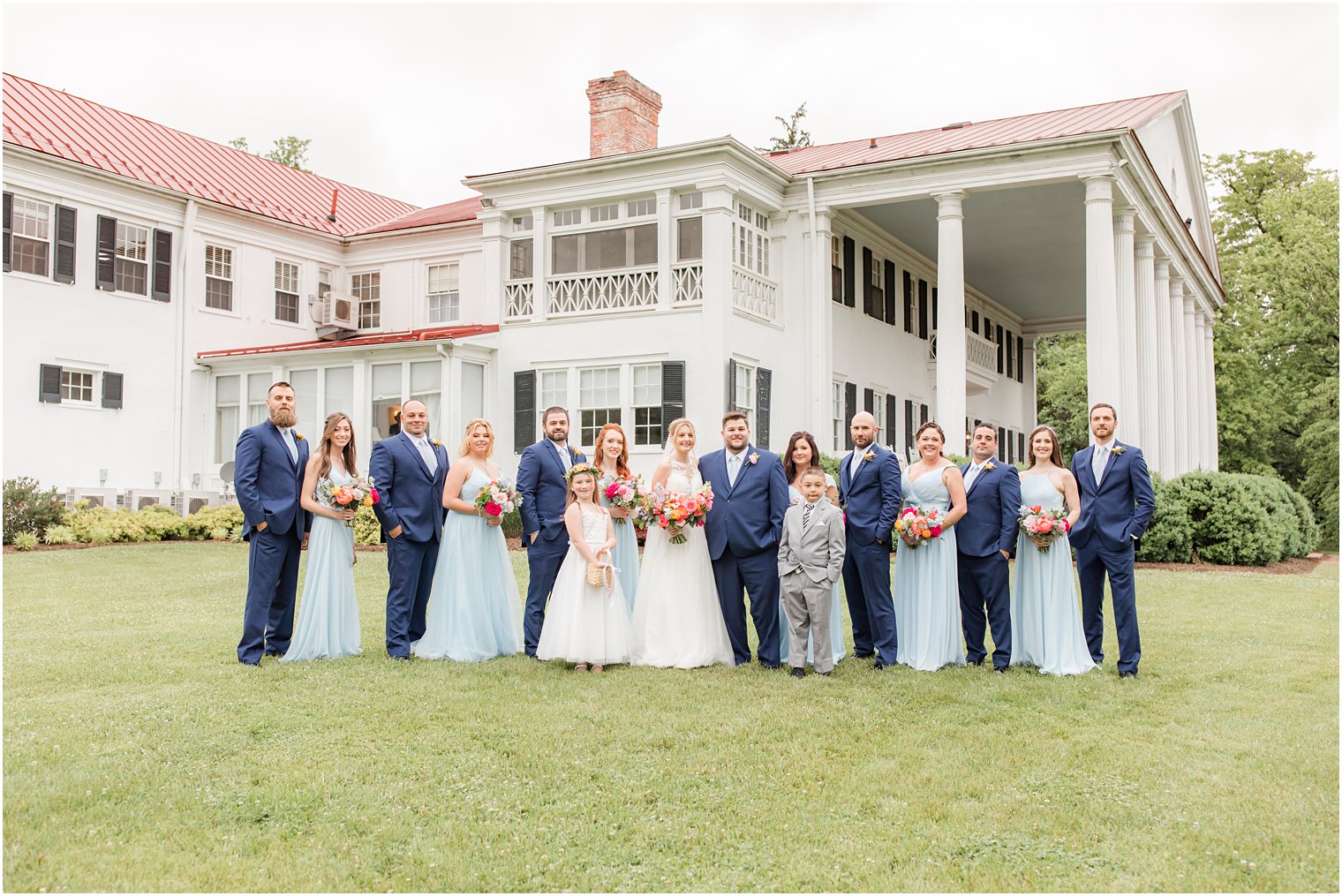 newlyweds pose with bridal party in light blue dresses and navy suits 