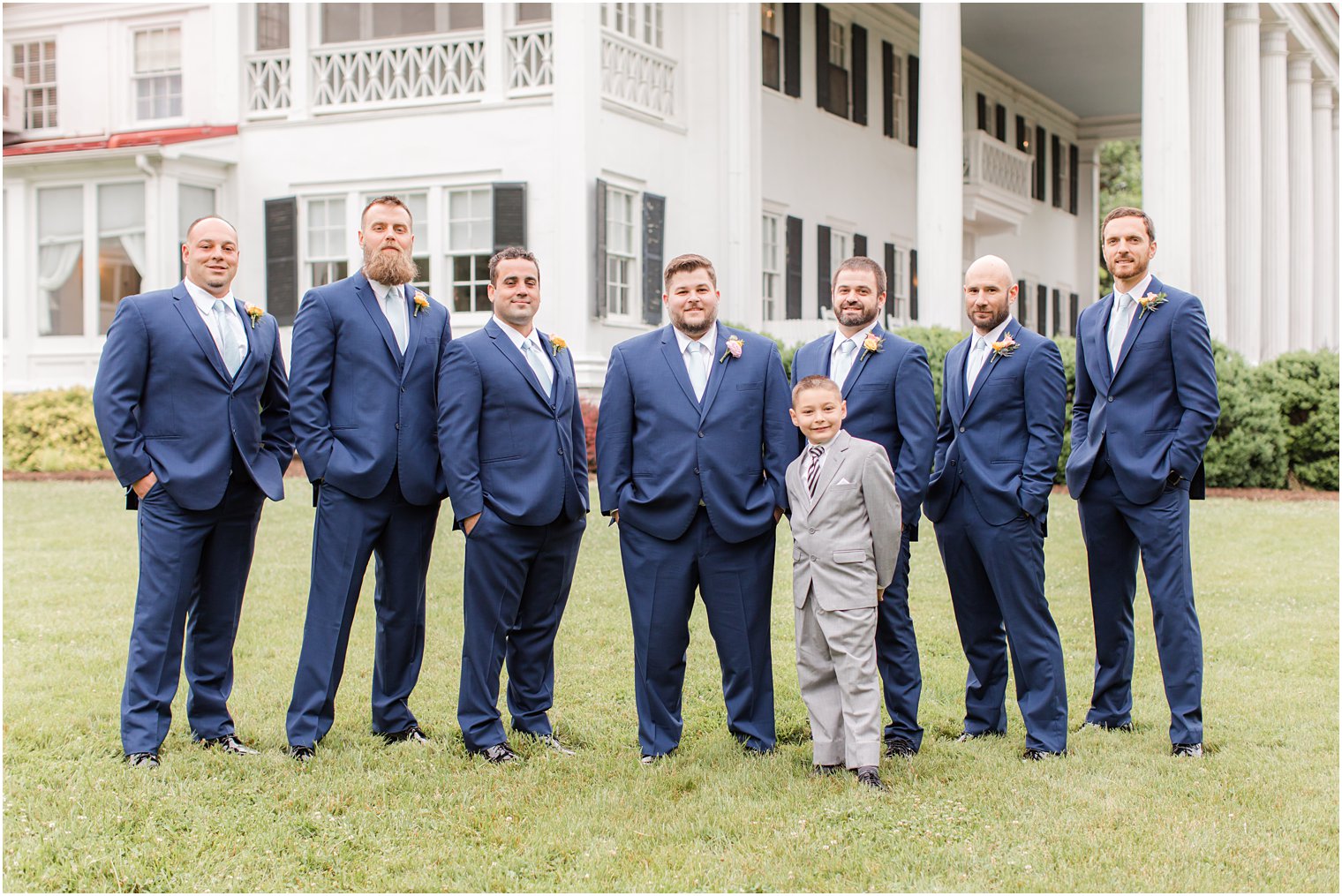 groom poses with groomsmen in navy suits in Berryville VA 
