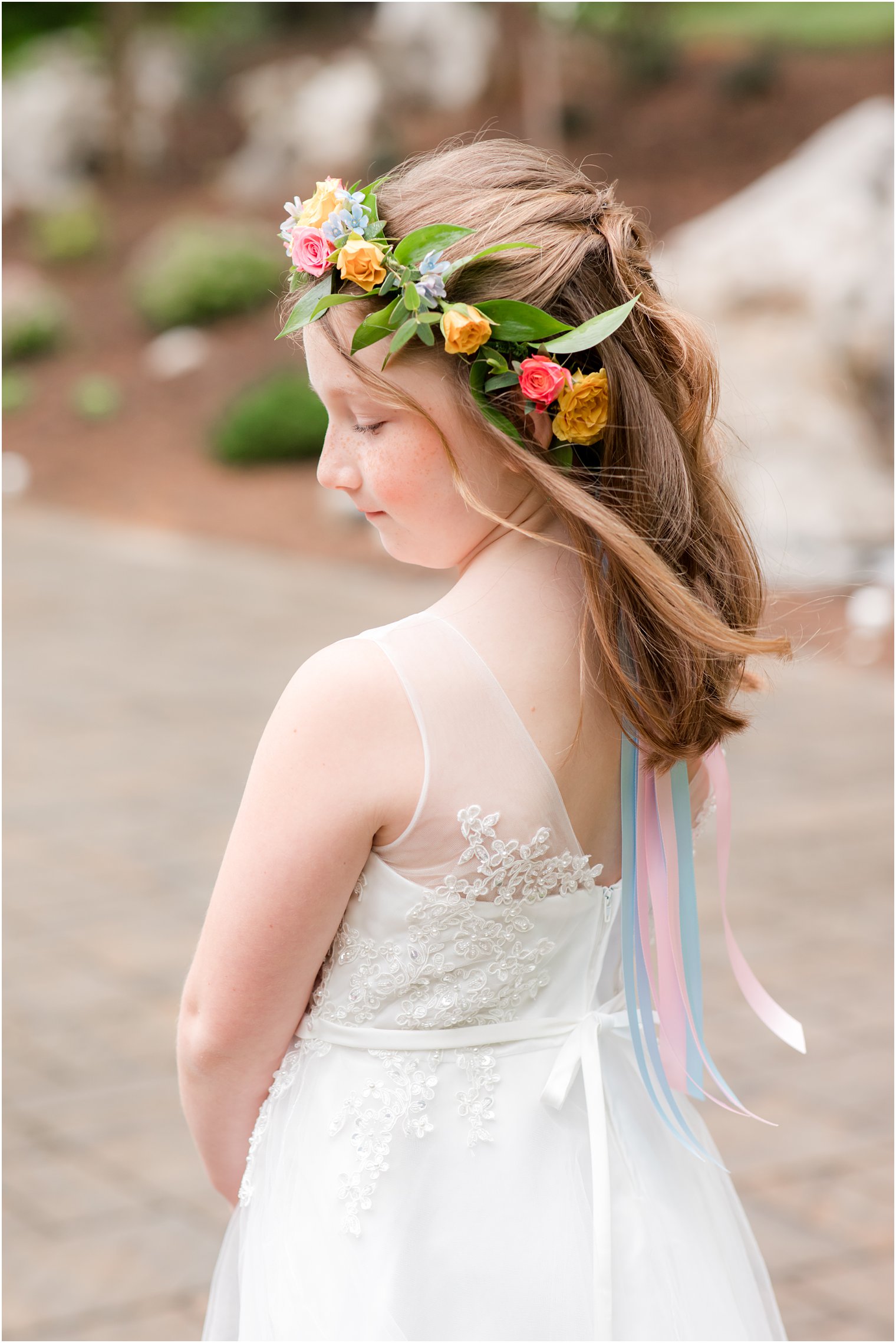 flower girl in colorful flower crown with pink and blue ribbons 