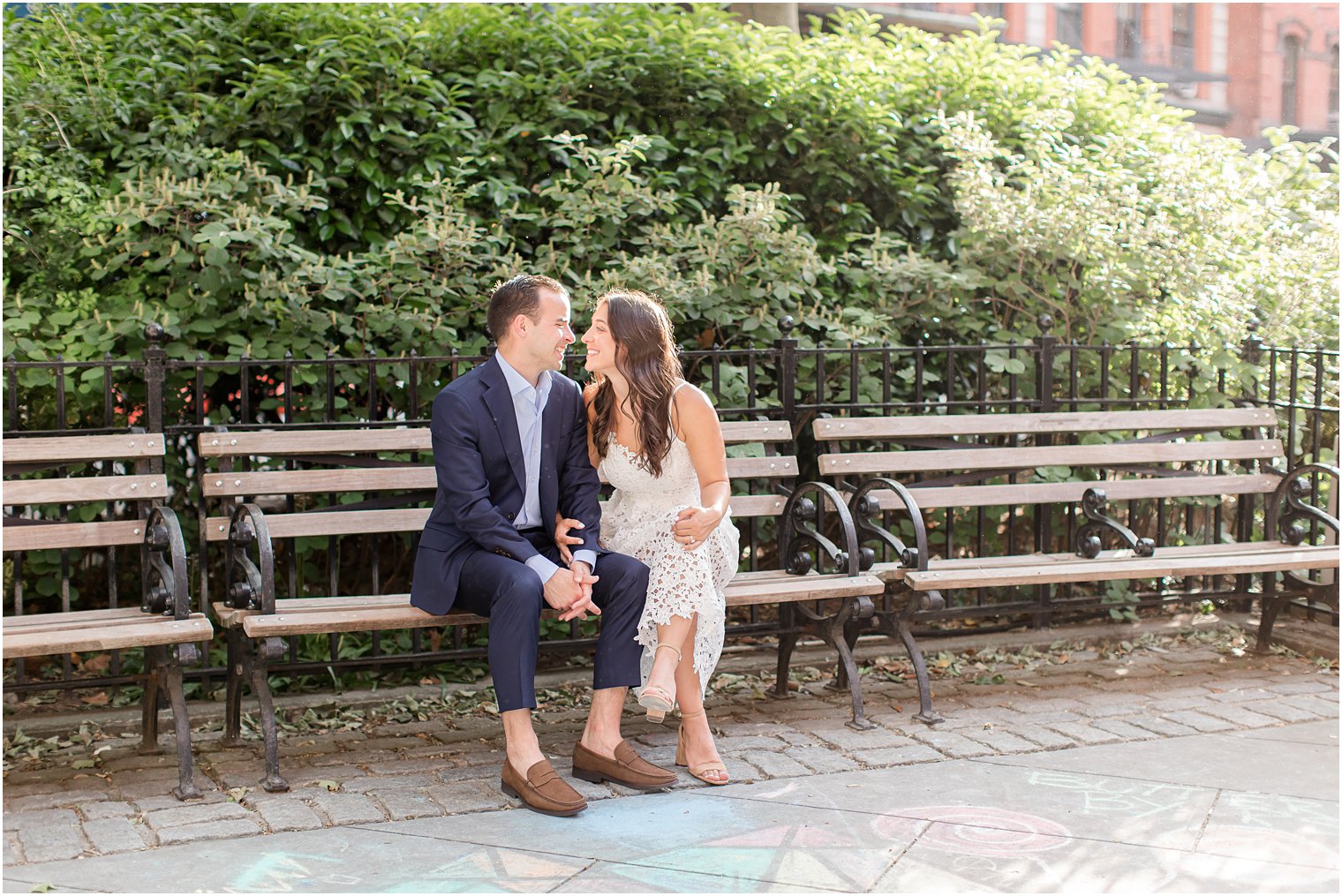 candid photo of couple laughing and sitting on a wooden bench in Duane Park in Tribeca