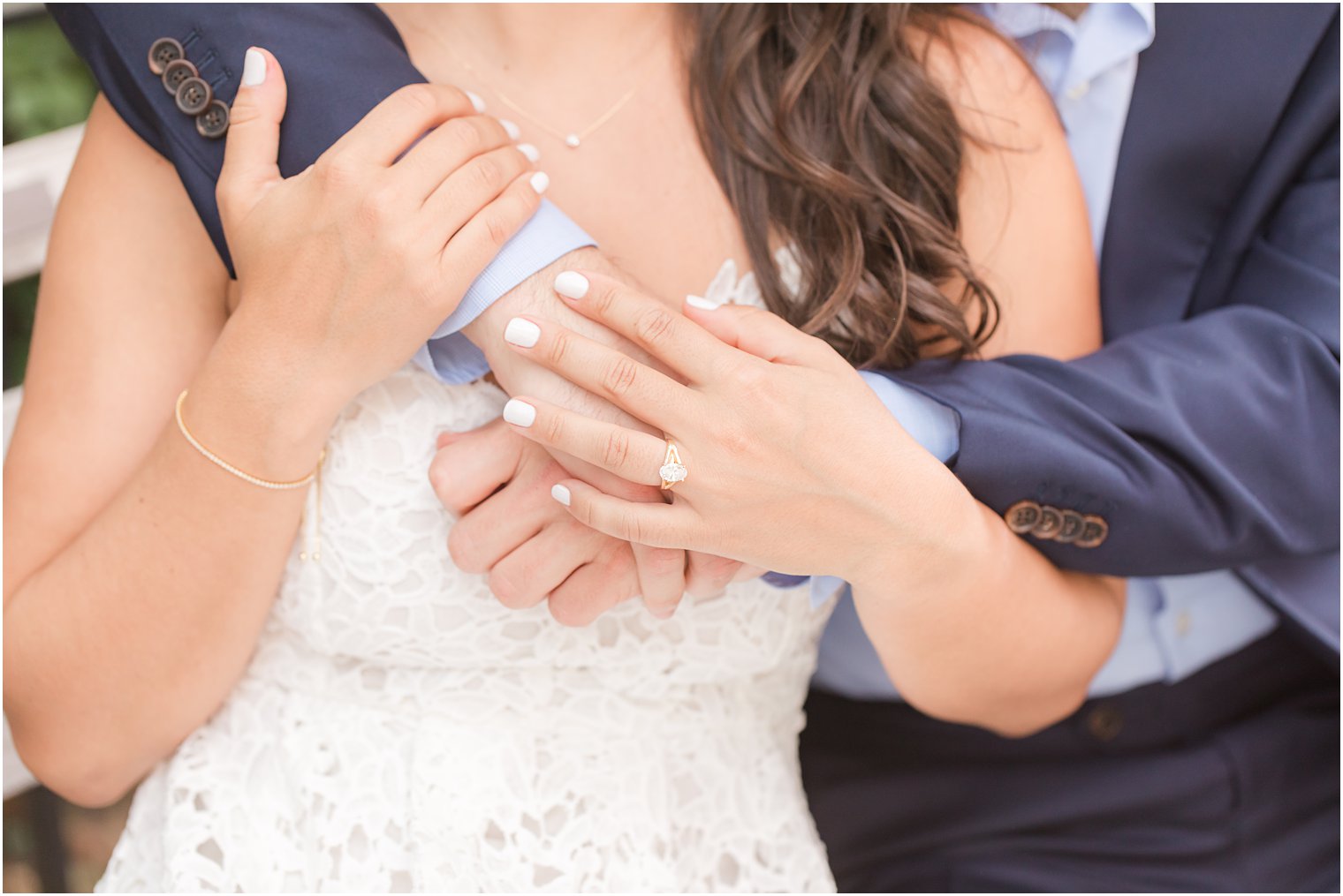 close-up of couple's arms holding each other and bride wearing engagement ring