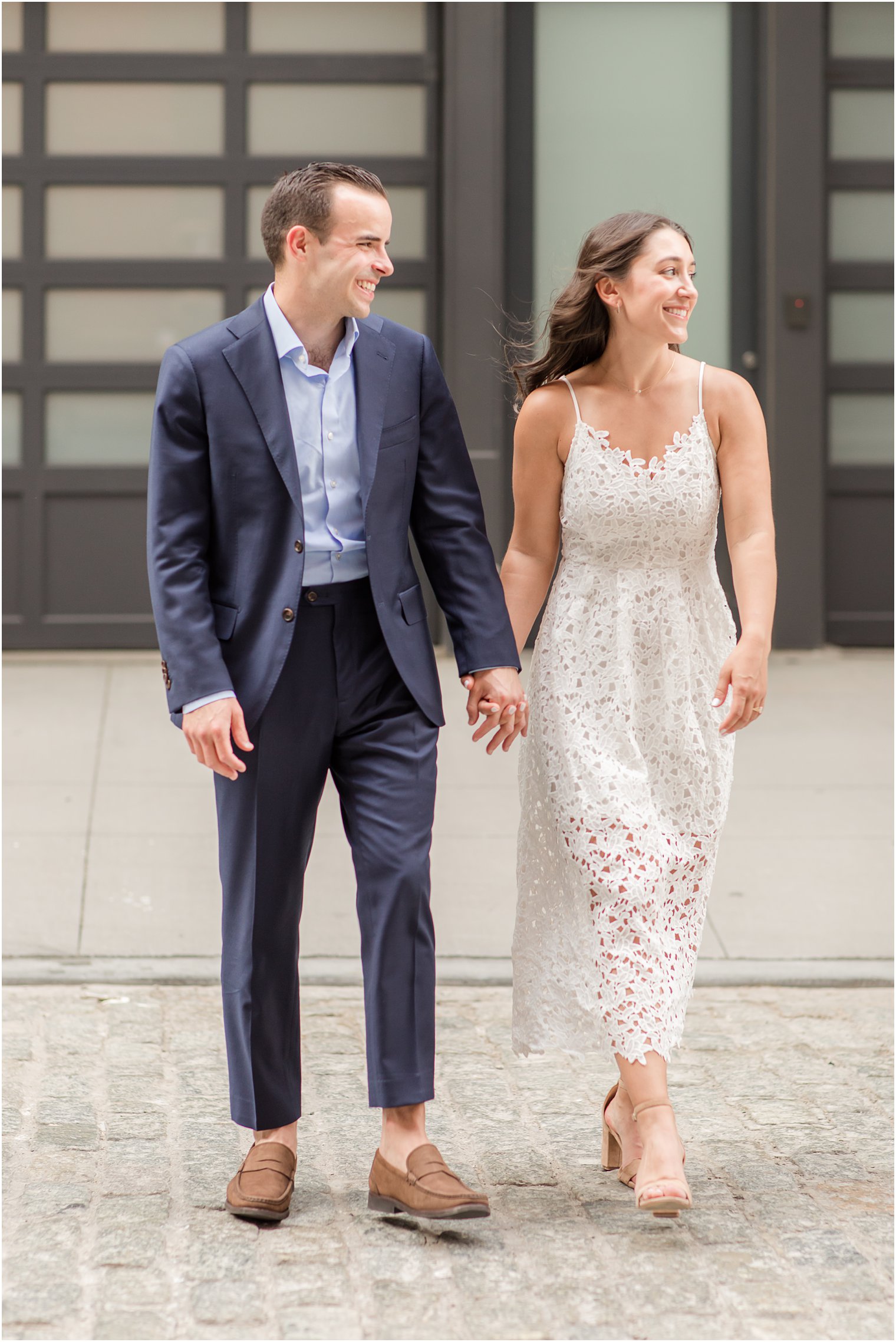 candid photo of couple crossing cobblestone street in Tribeca