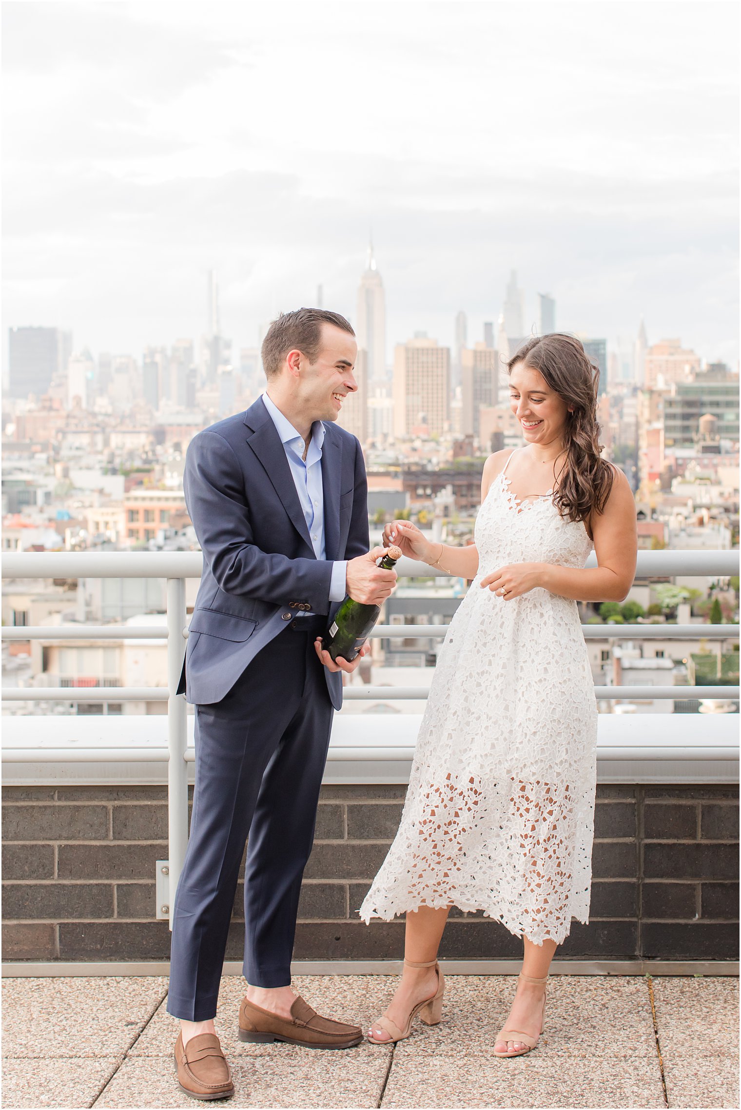 engaged couple opening bottle of champagne on Tribeca rooftop 