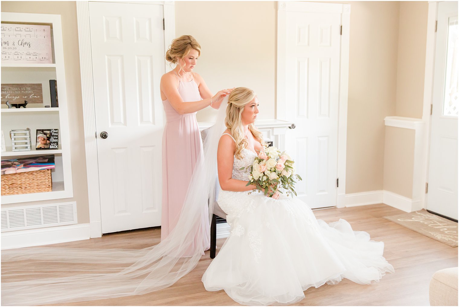 bridesmaid helps bride with veil before NJ wedding at Brigalias