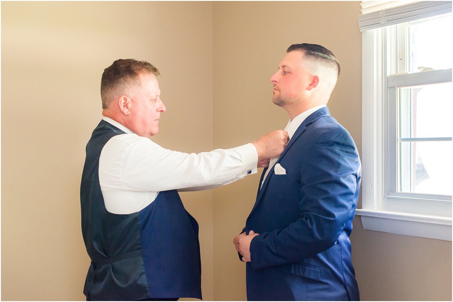 father adjusts tie for groom before Brigalias wedding day
