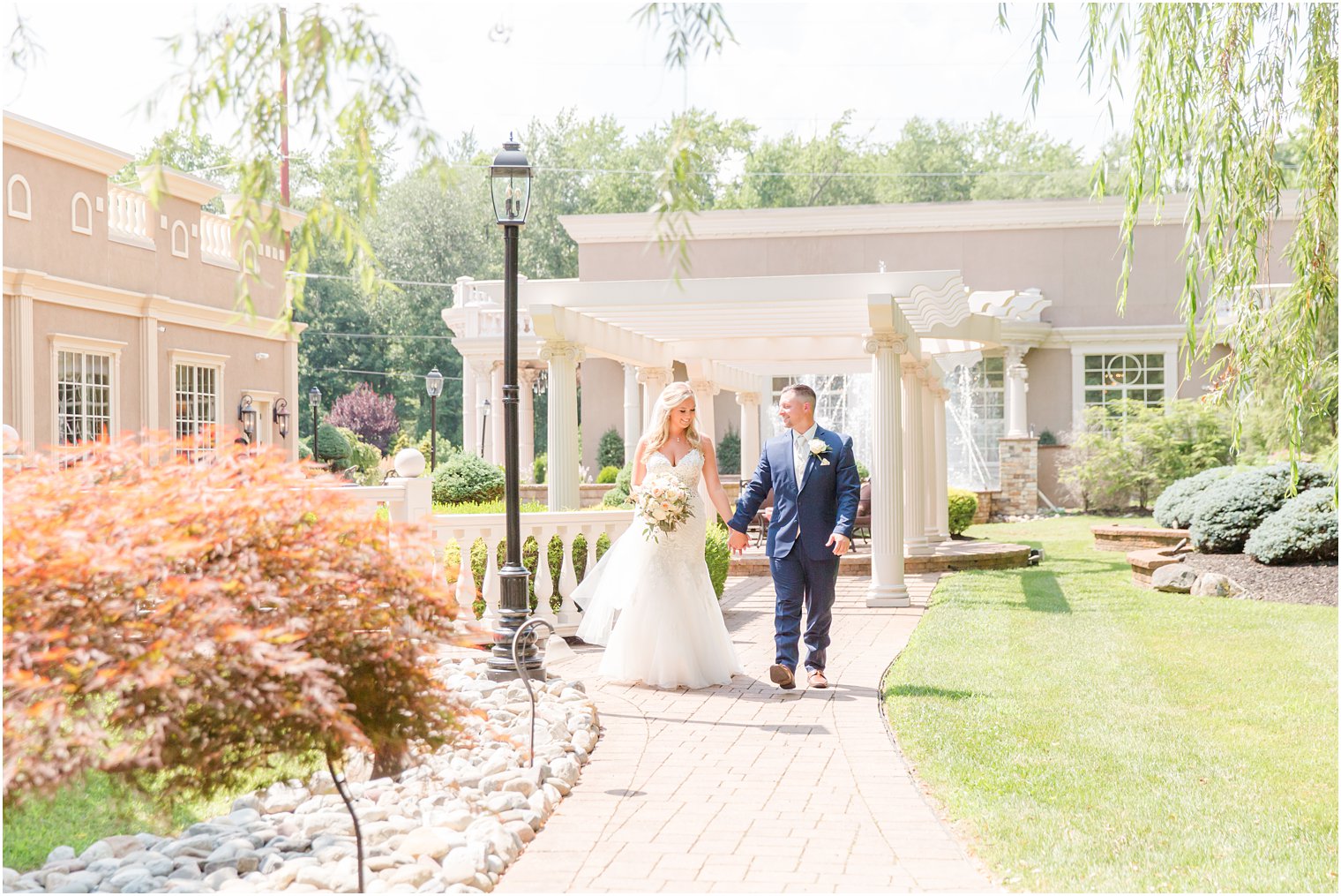bride and groom hold hands walking through garden at Brigalias