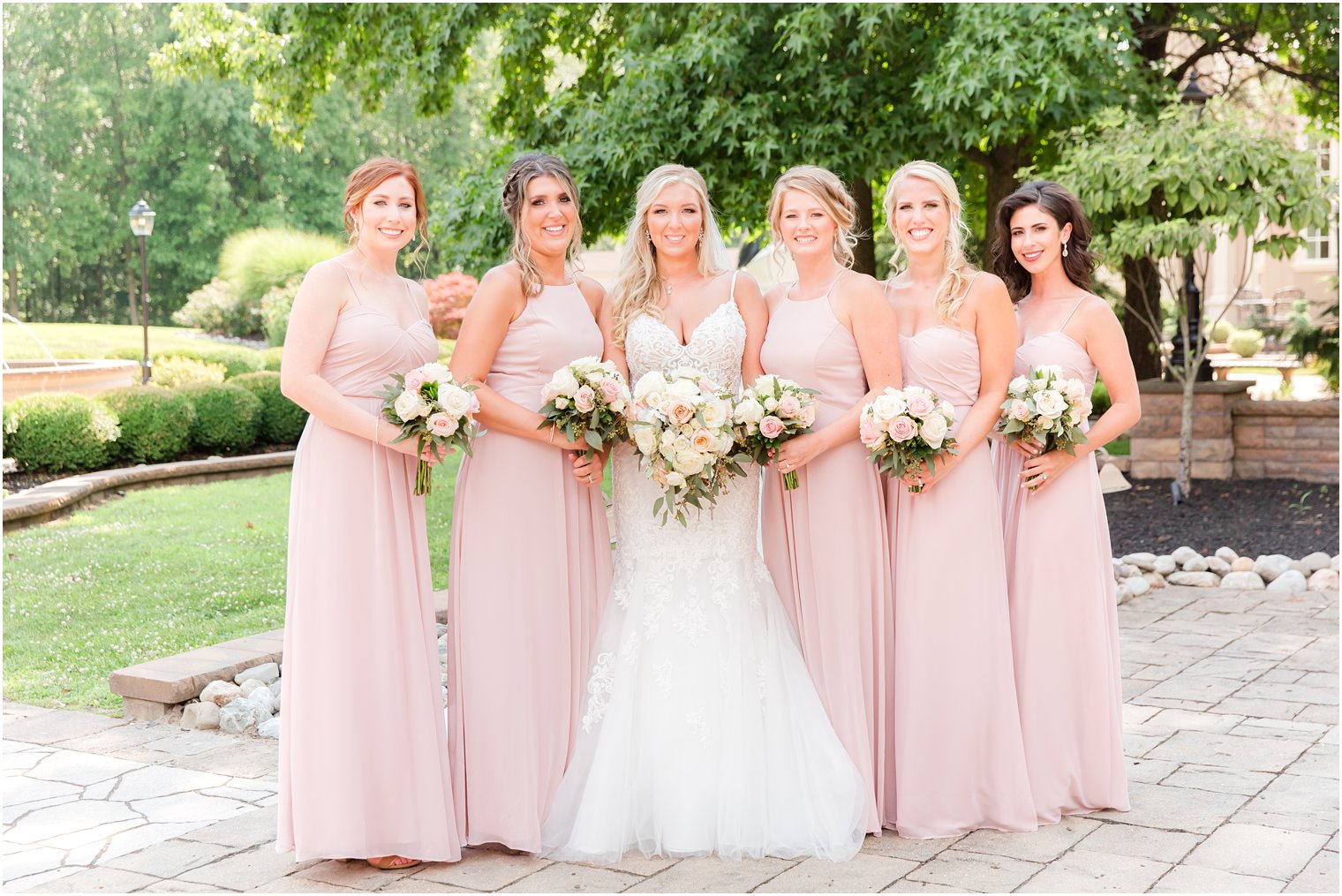 bride poses with bridesmaids in light pink gowns before Brigalias wedding