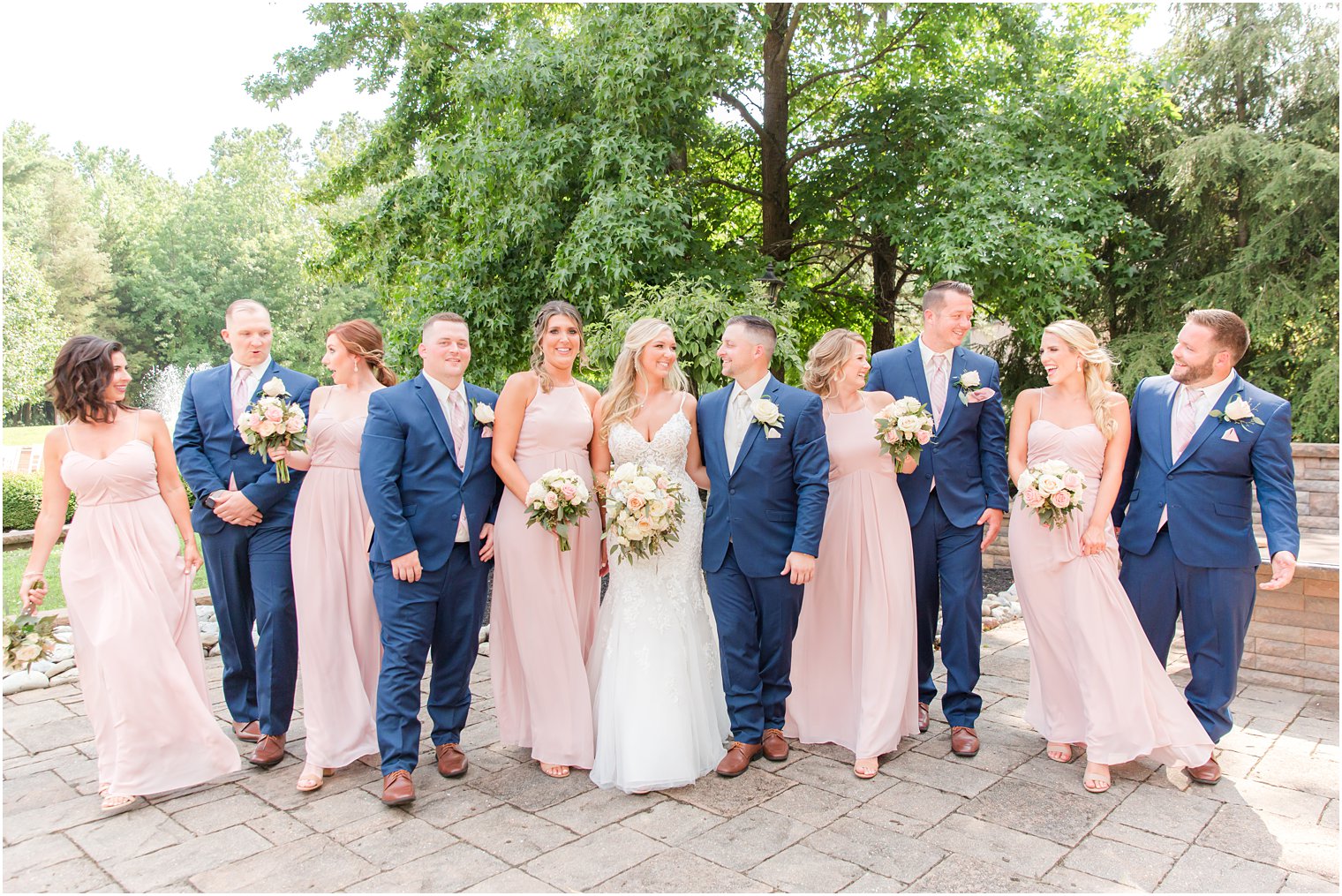 wedding party in navy blue and pink dresses walk with bride and groom