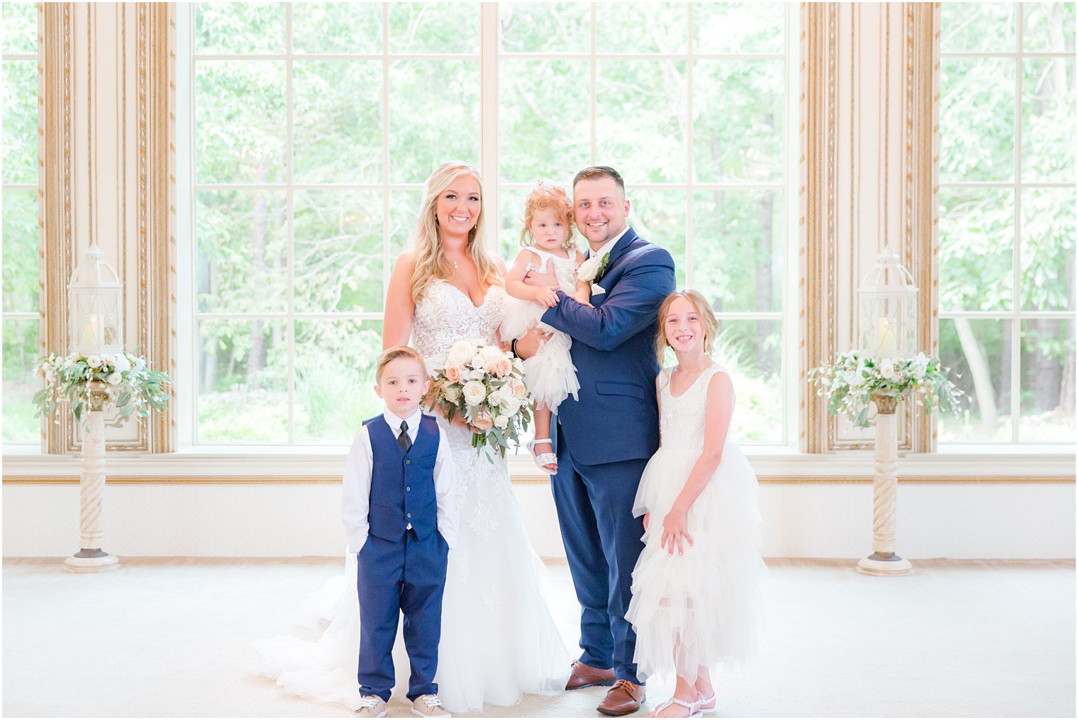newlyweds pose with two flower girls and ring bearer after wedding ceremony 