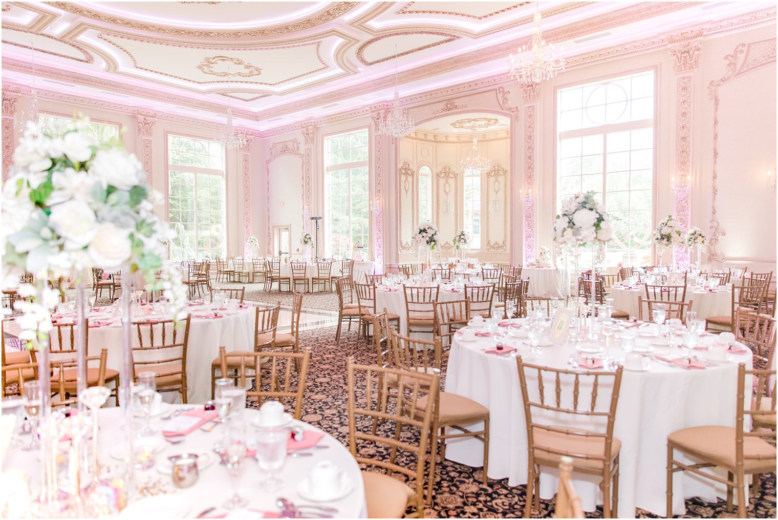 wedding reception in ballroom with pink uplighting and gold chivari chairs 