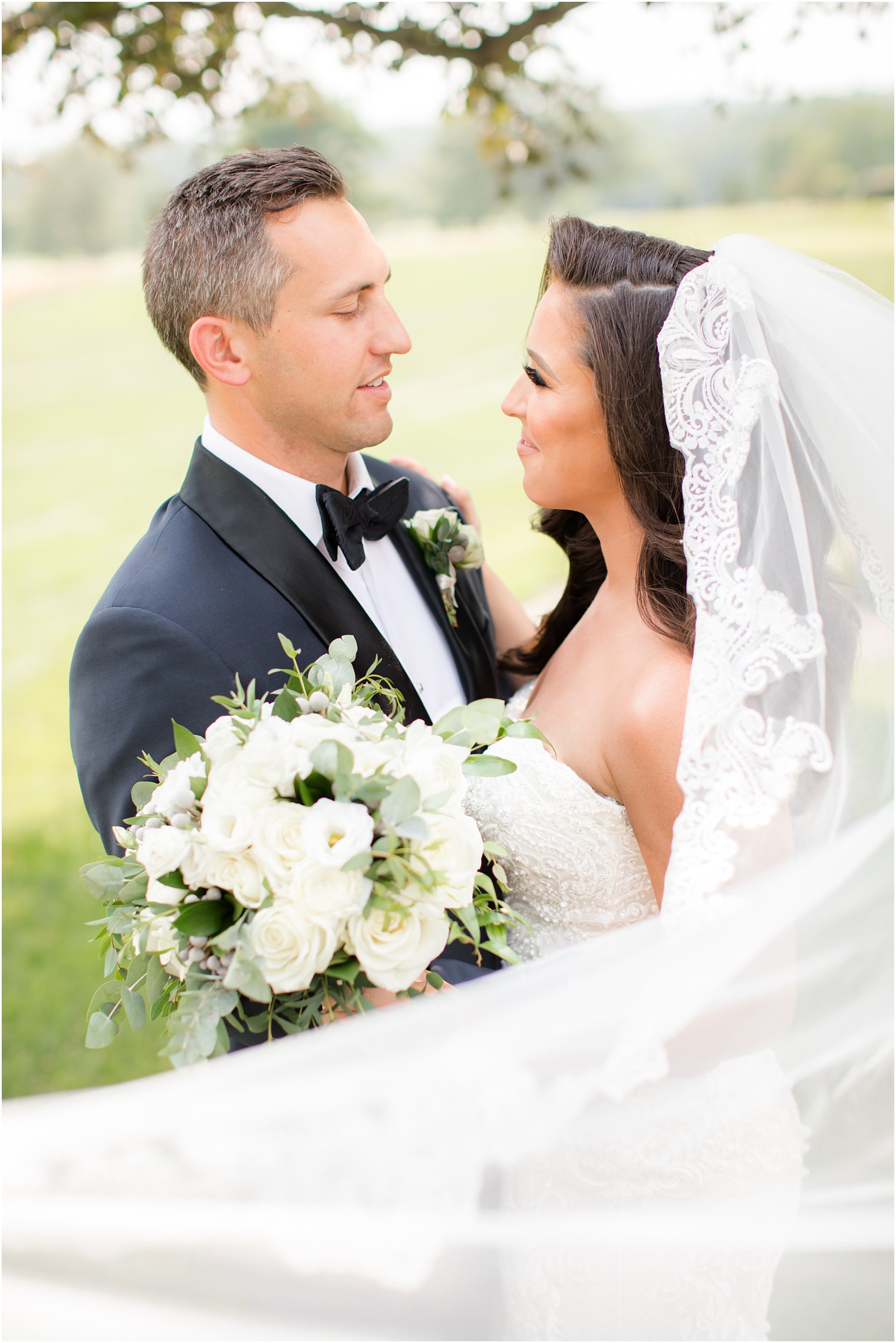 bride and groom look at each other with bride's veil floating around them