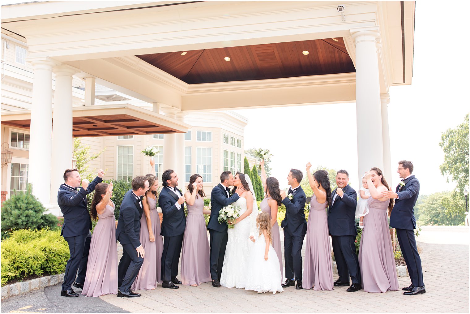 wedding party cheers while bride and groom kiss outside Navesink Country Club