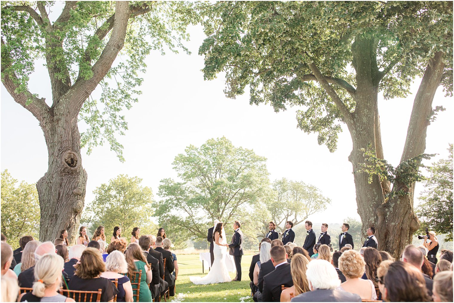 newlyweds stand together among trees at Navesink Country Club