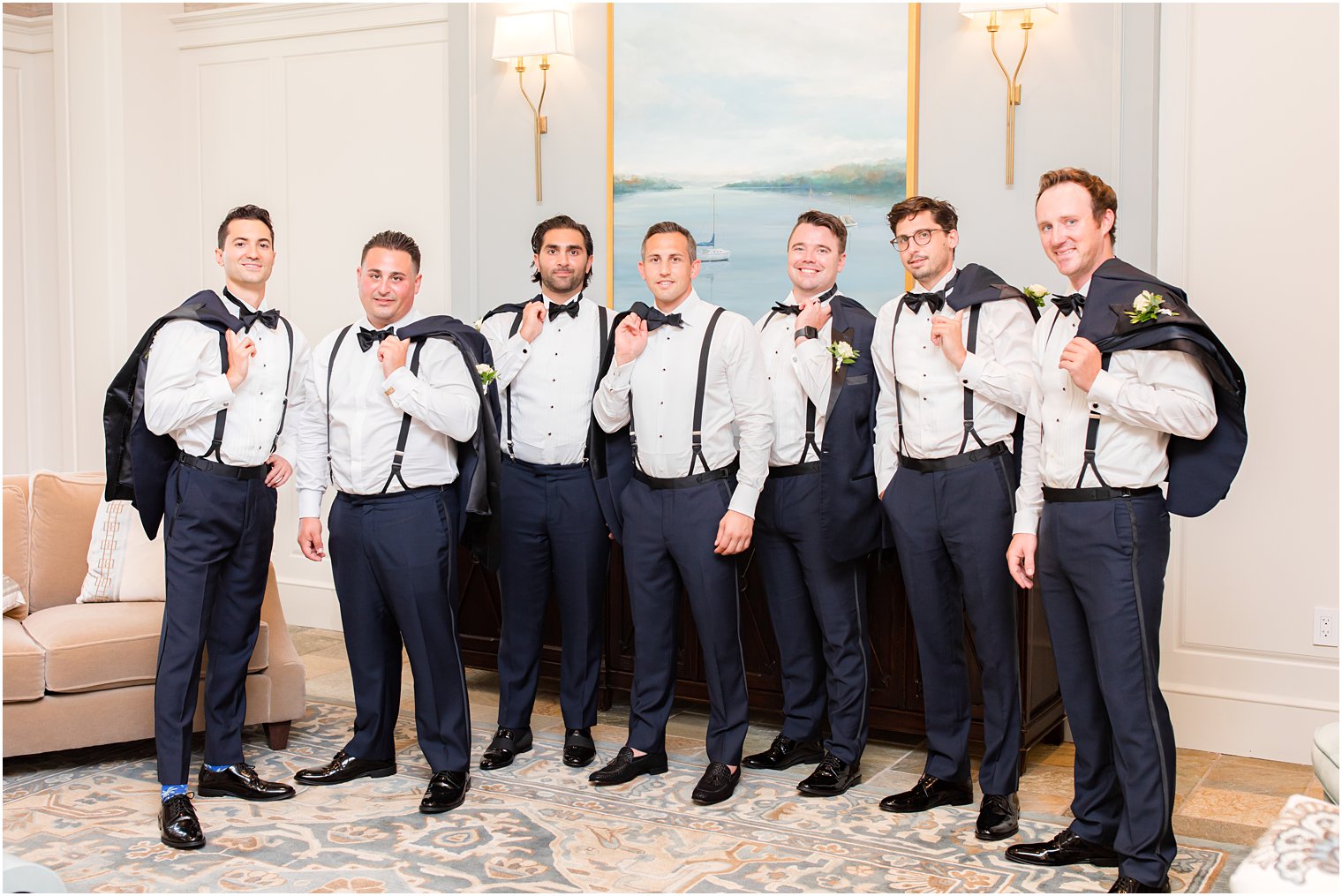 groom and groomsmen pose with jackets over shoulders