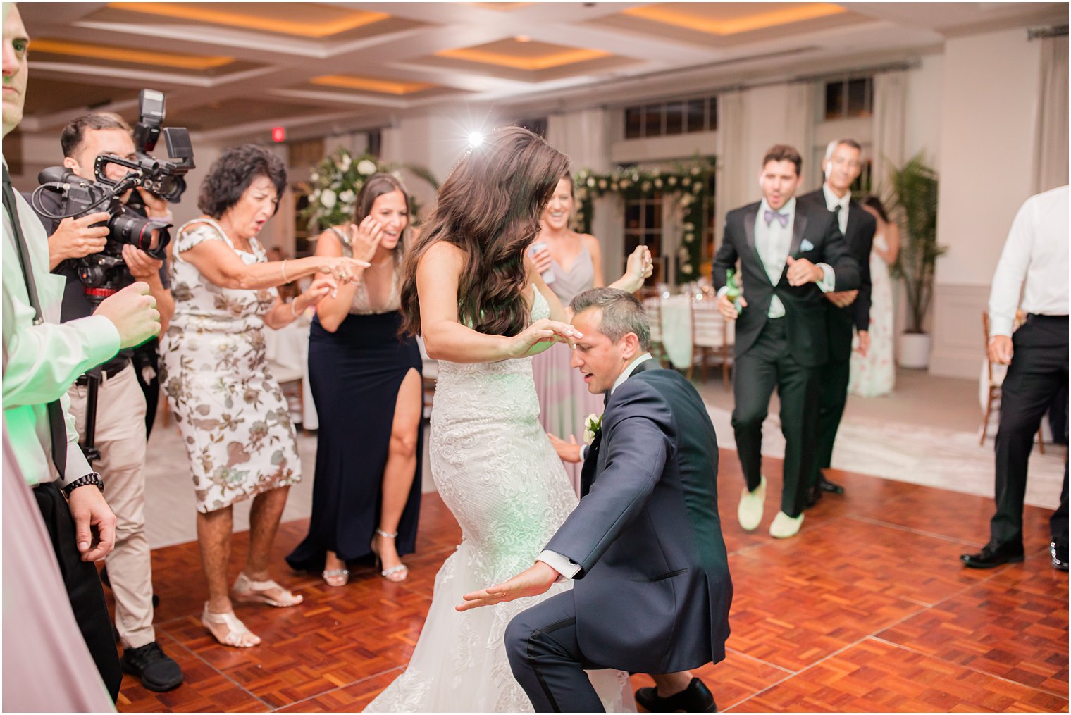 newlyweds dance during wedding reception on dance floor with guests