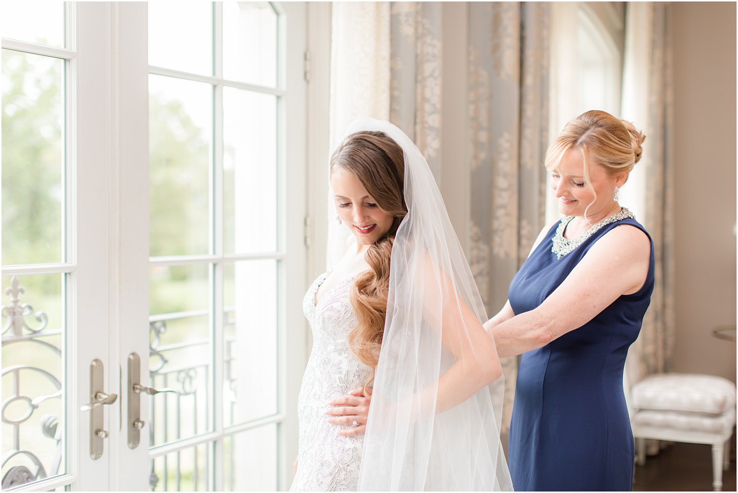 mom helps bride with veil on wedding day