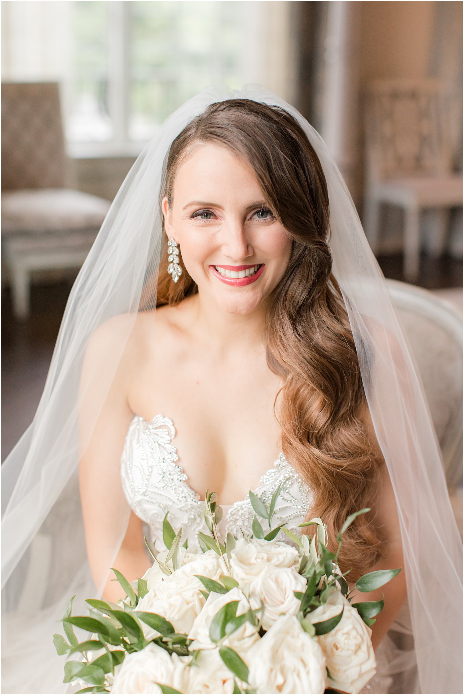 bride holds bouquet of white flowers sitting in bridal suite of Park Chateau Estate