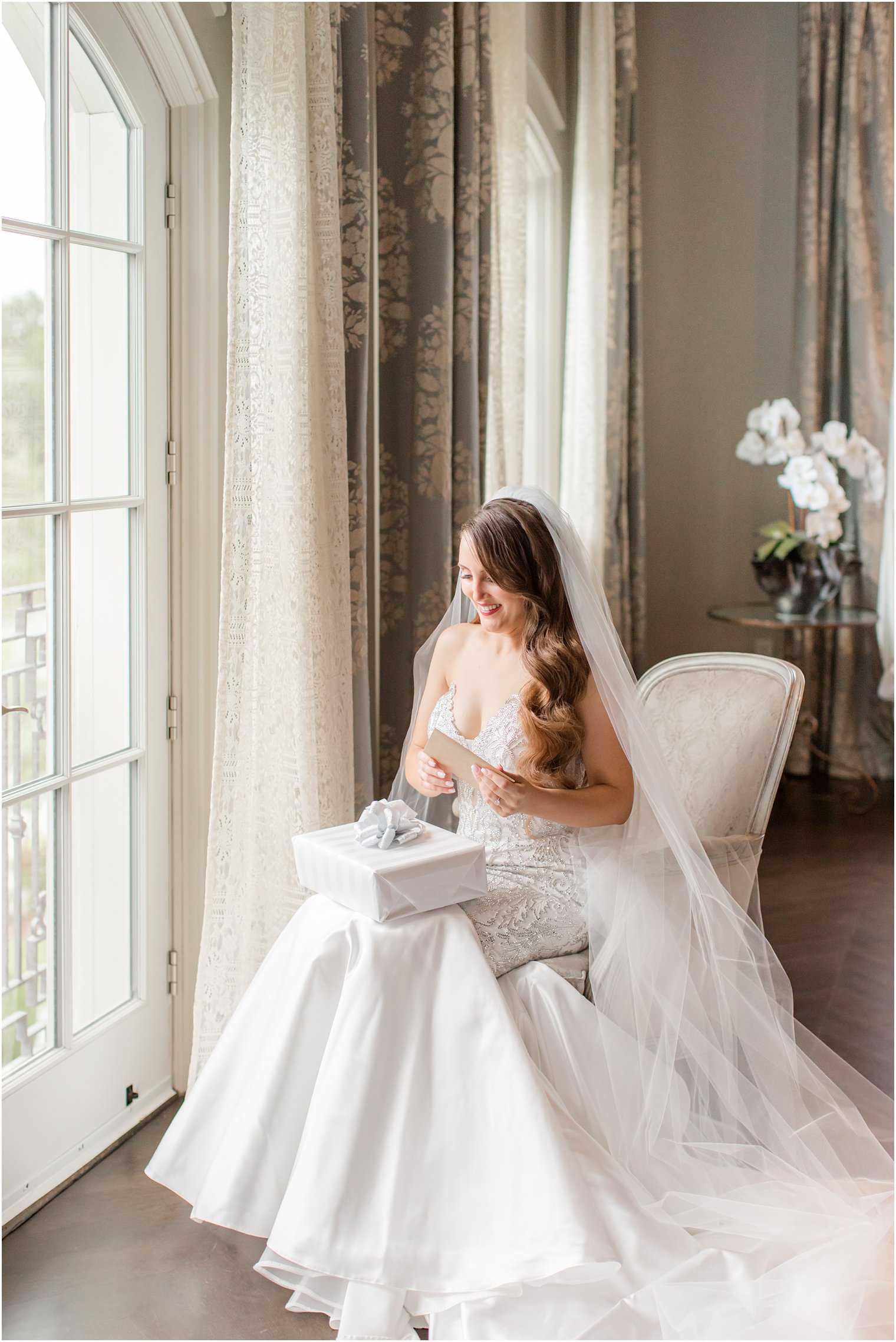 bride opens gift from groom on wedding day in bridal suite of Park Chateau Estate