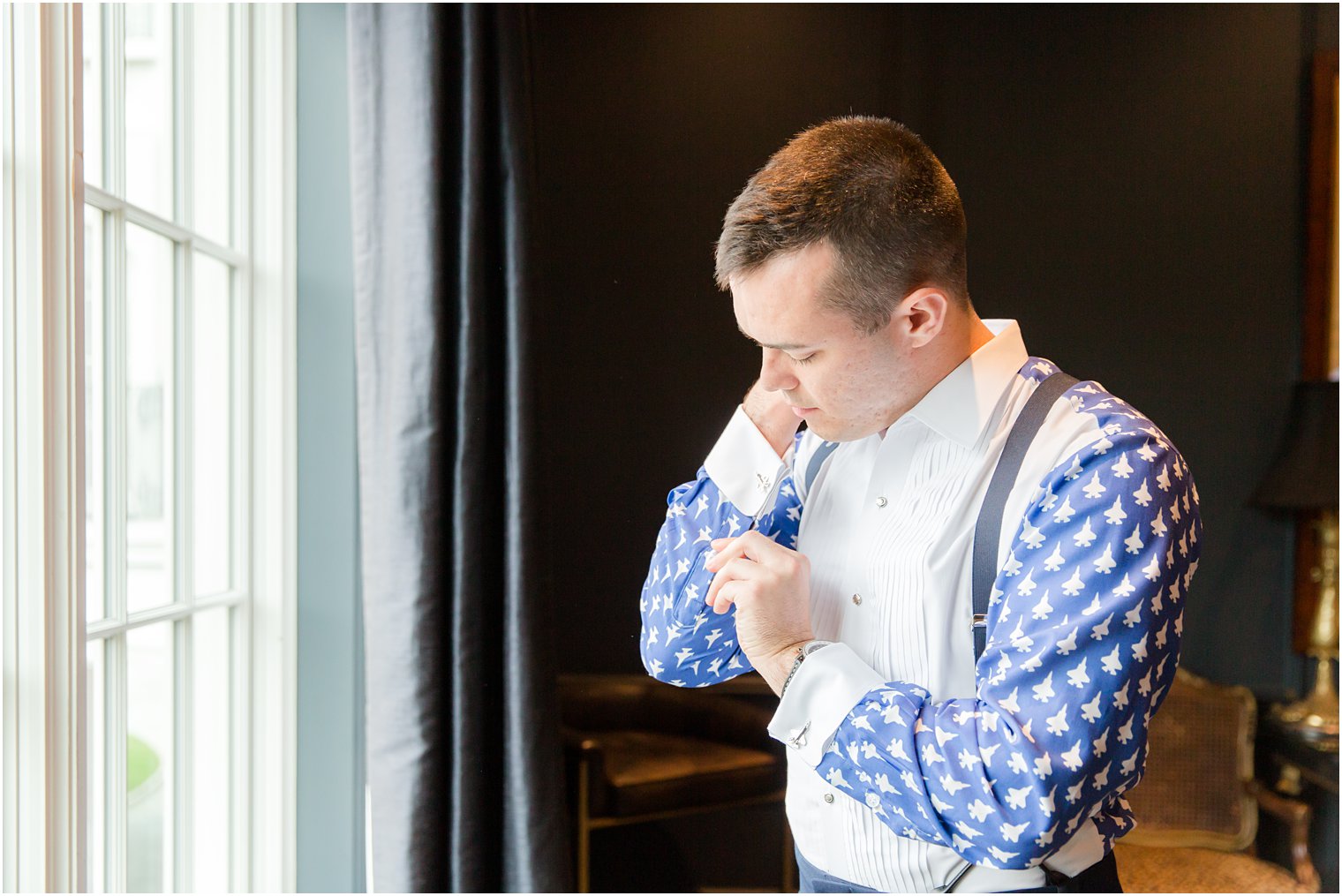 groom puts custom cufflinks on custom shirt for wedding day