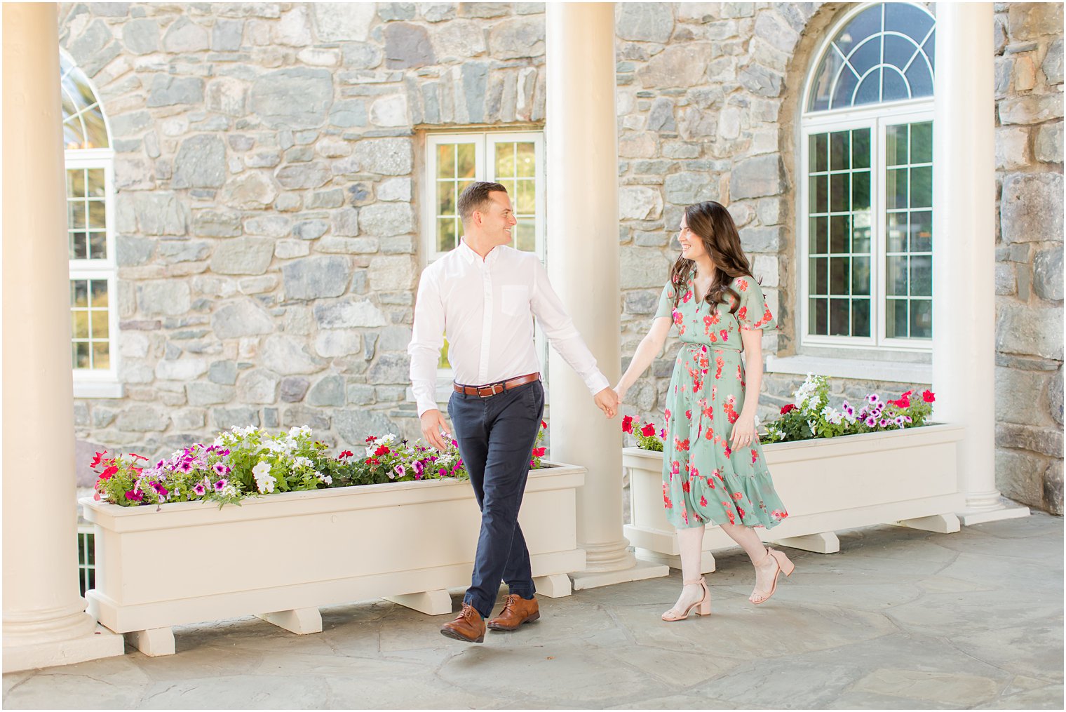 engaged couple holds hands walking through covered patio at Skytop Lodge