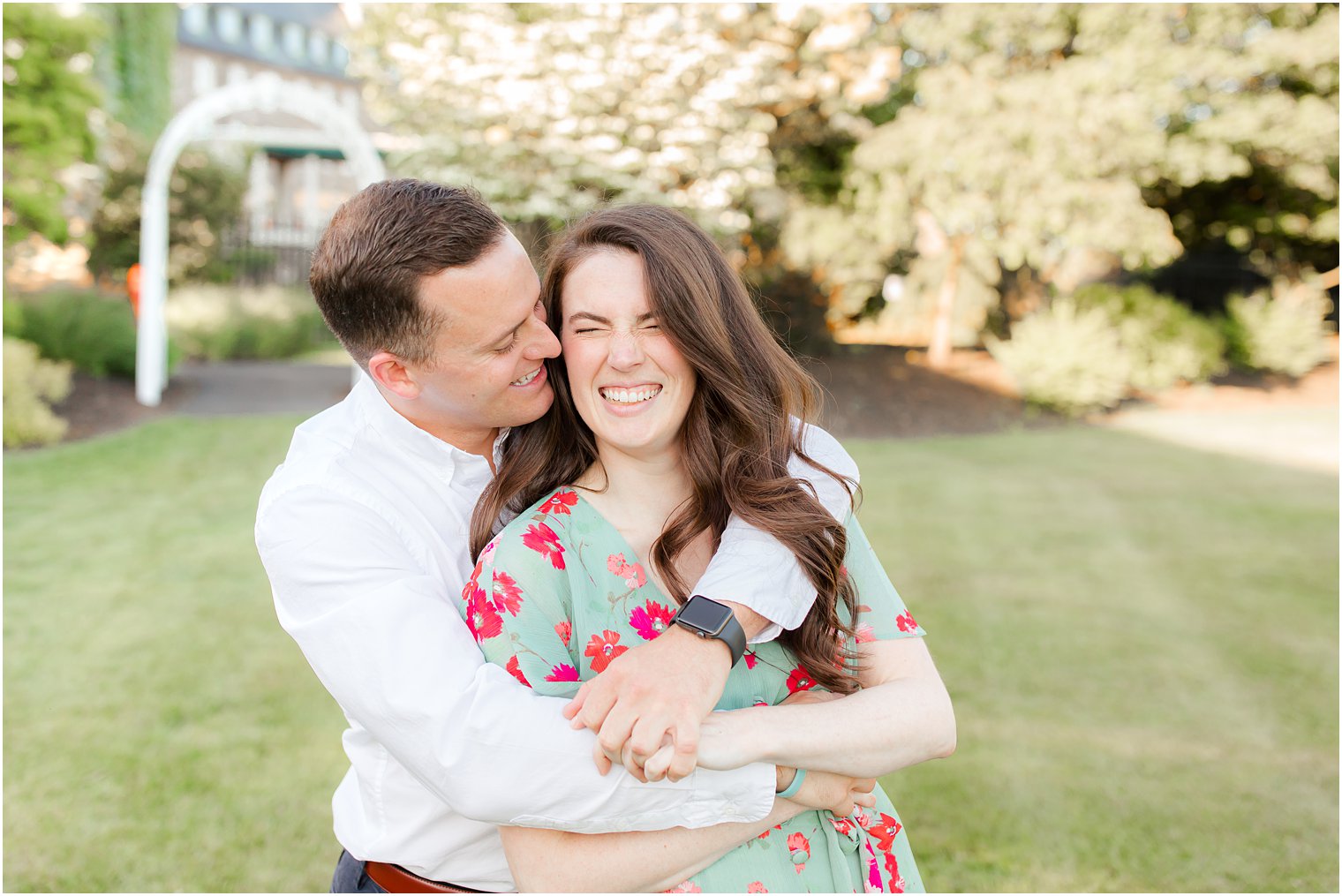 bride and groom hug and laugh during engagement portraits in courtyard 