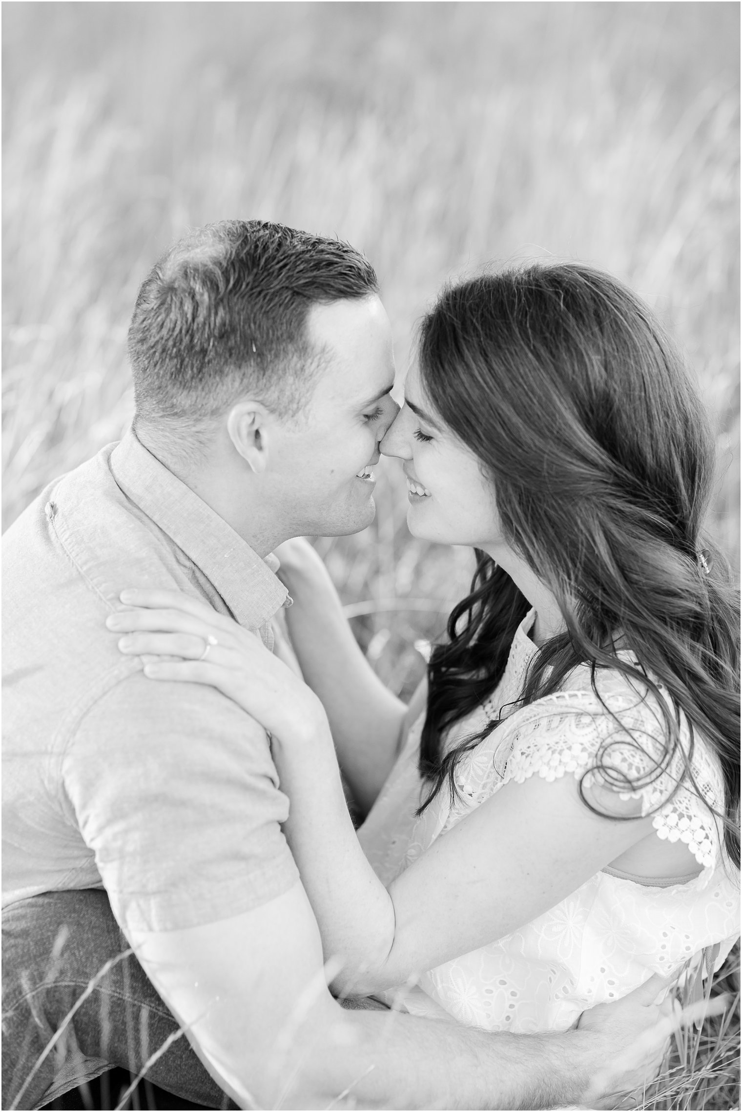 bride and groom sit hugging in grass during engagement portraits in PA