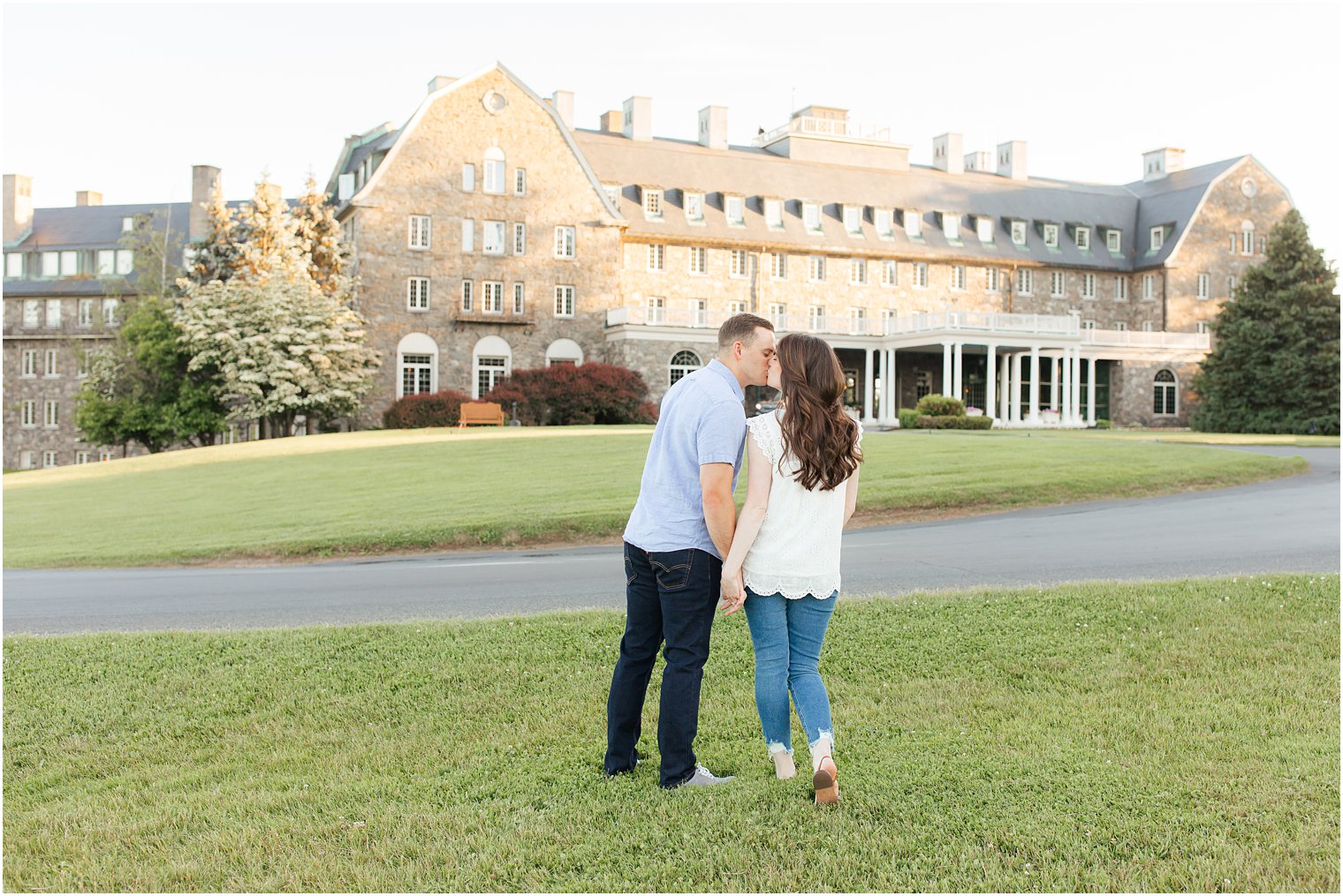 bride and groom kiss on lawn outside Skytop Lodge during engagement photos