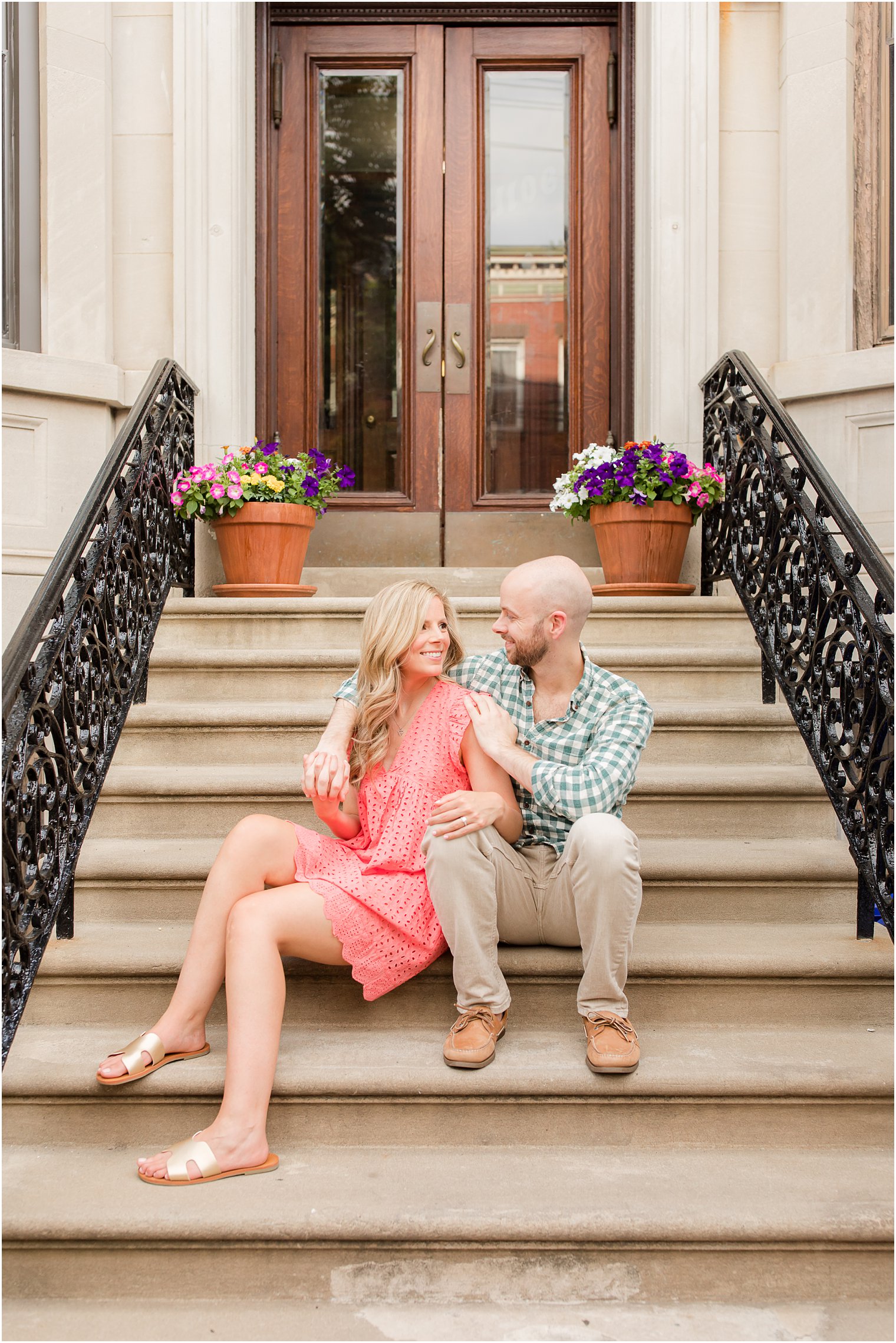 couple sits on steps during summer Hoboken engagement session