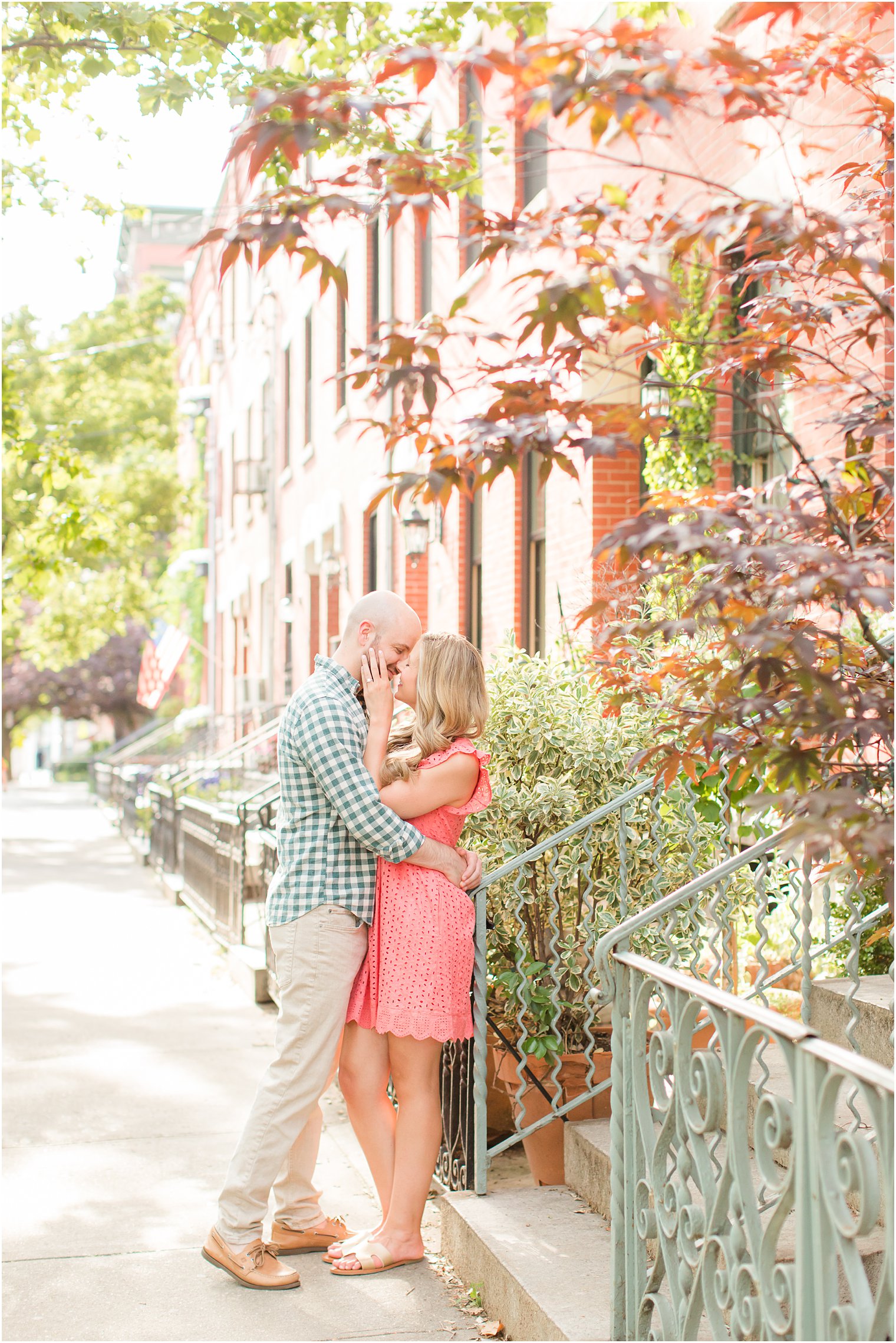 engaged couple kisses on street during summer Hoboken engagement session