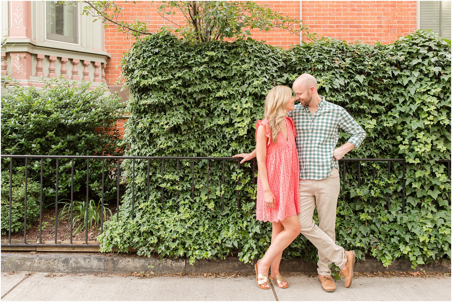engaged couple pose by ivy wall during summer Hoboken engagement session
