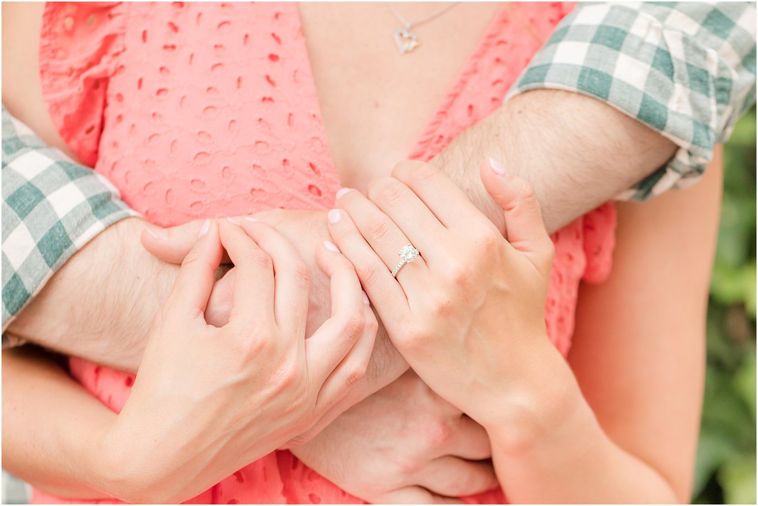 bride holds groom's arm showing off engagement ring