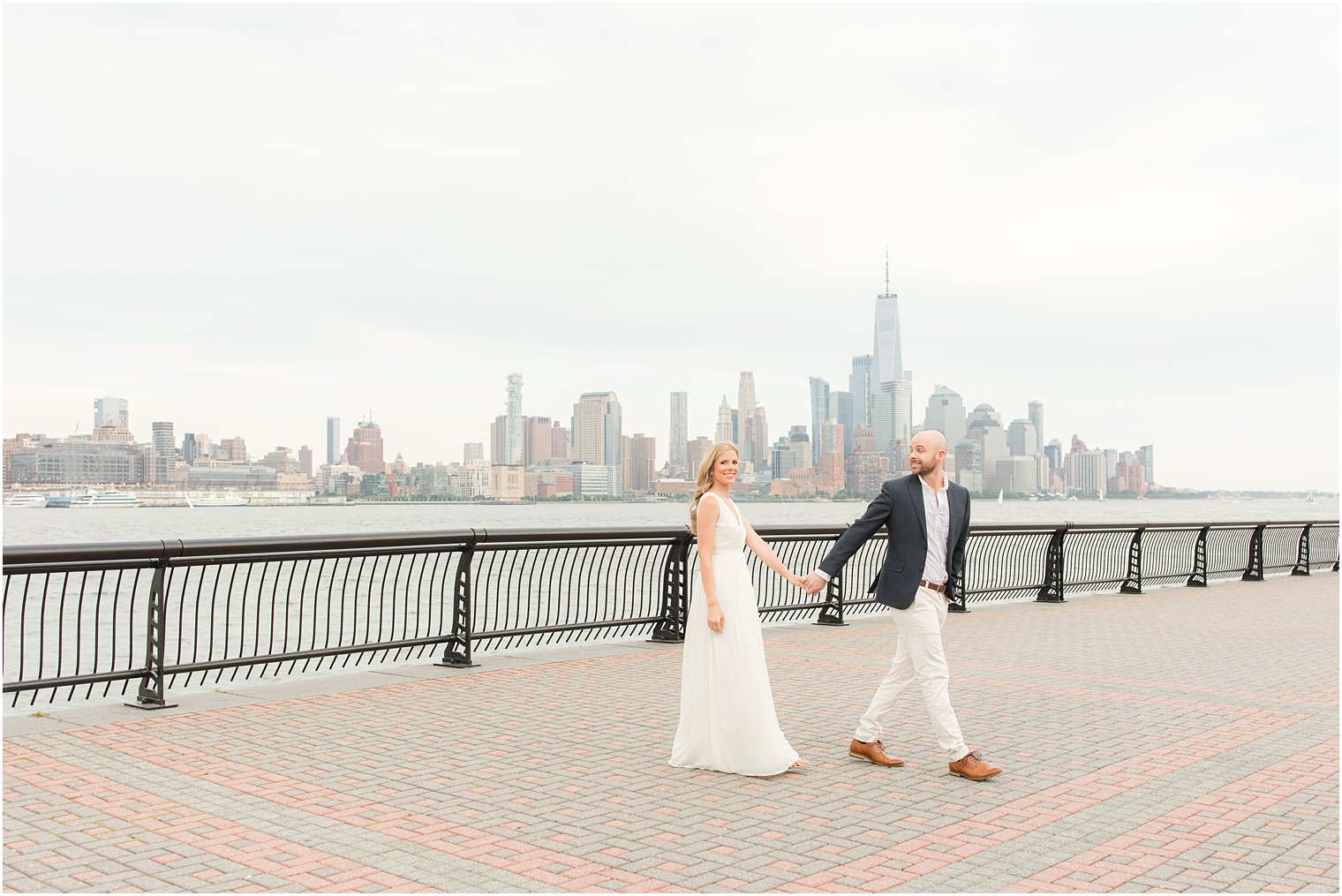 engaged couple walks along waterfront in Hoboken NJ