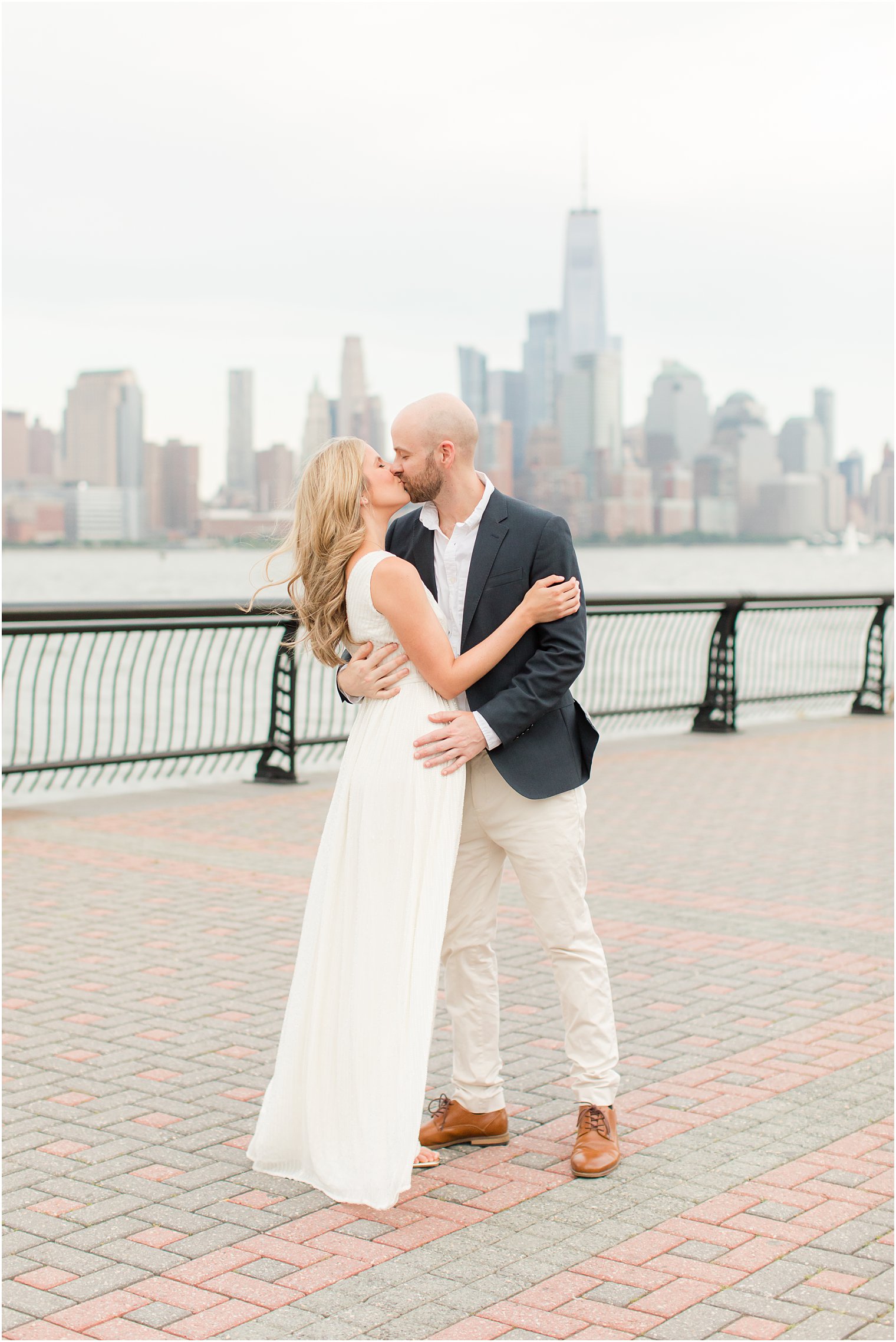 engaged couple in white dress and suit kiss during summer Hoboken engagement session