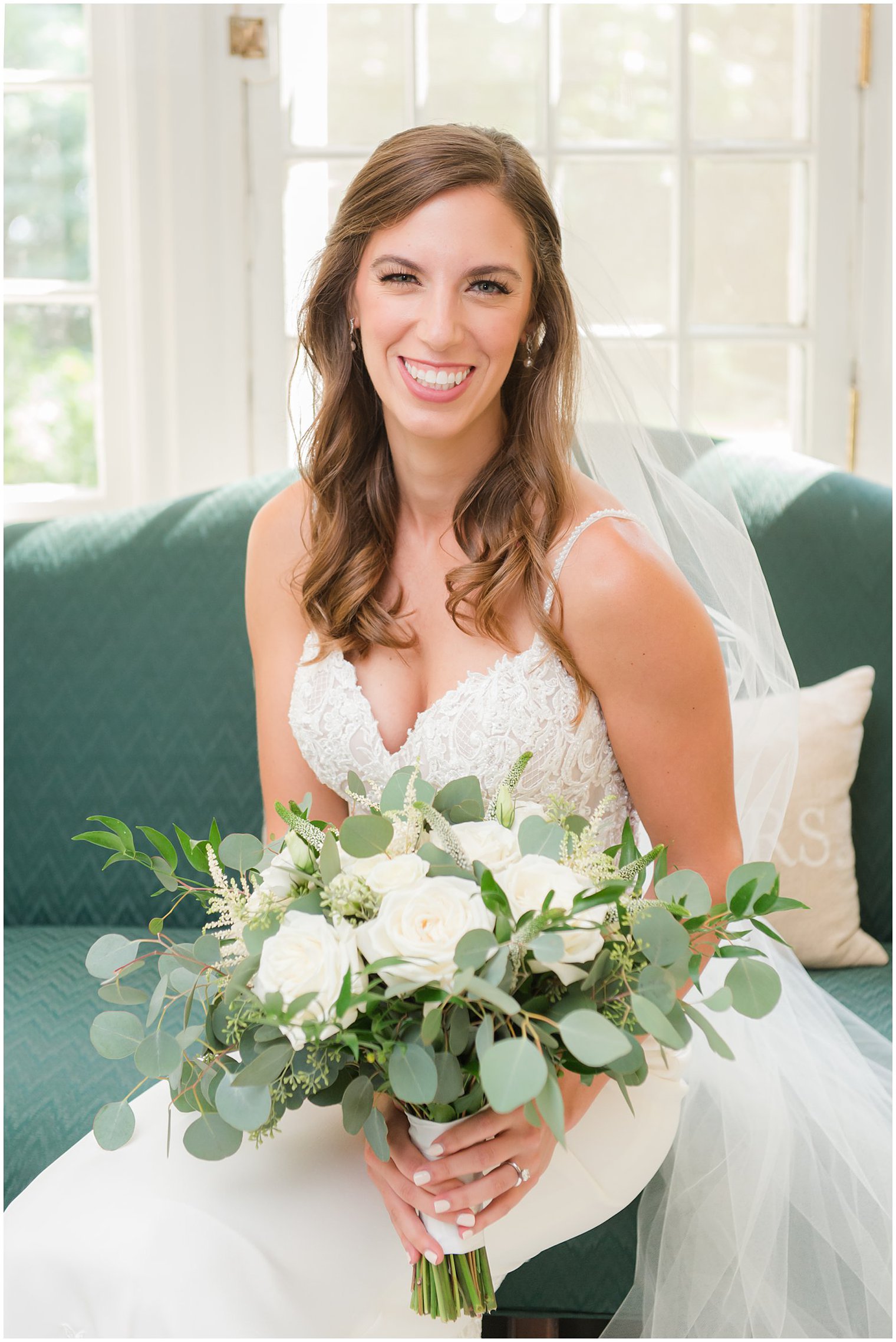 bride smiles holding bouquet of ivory roses