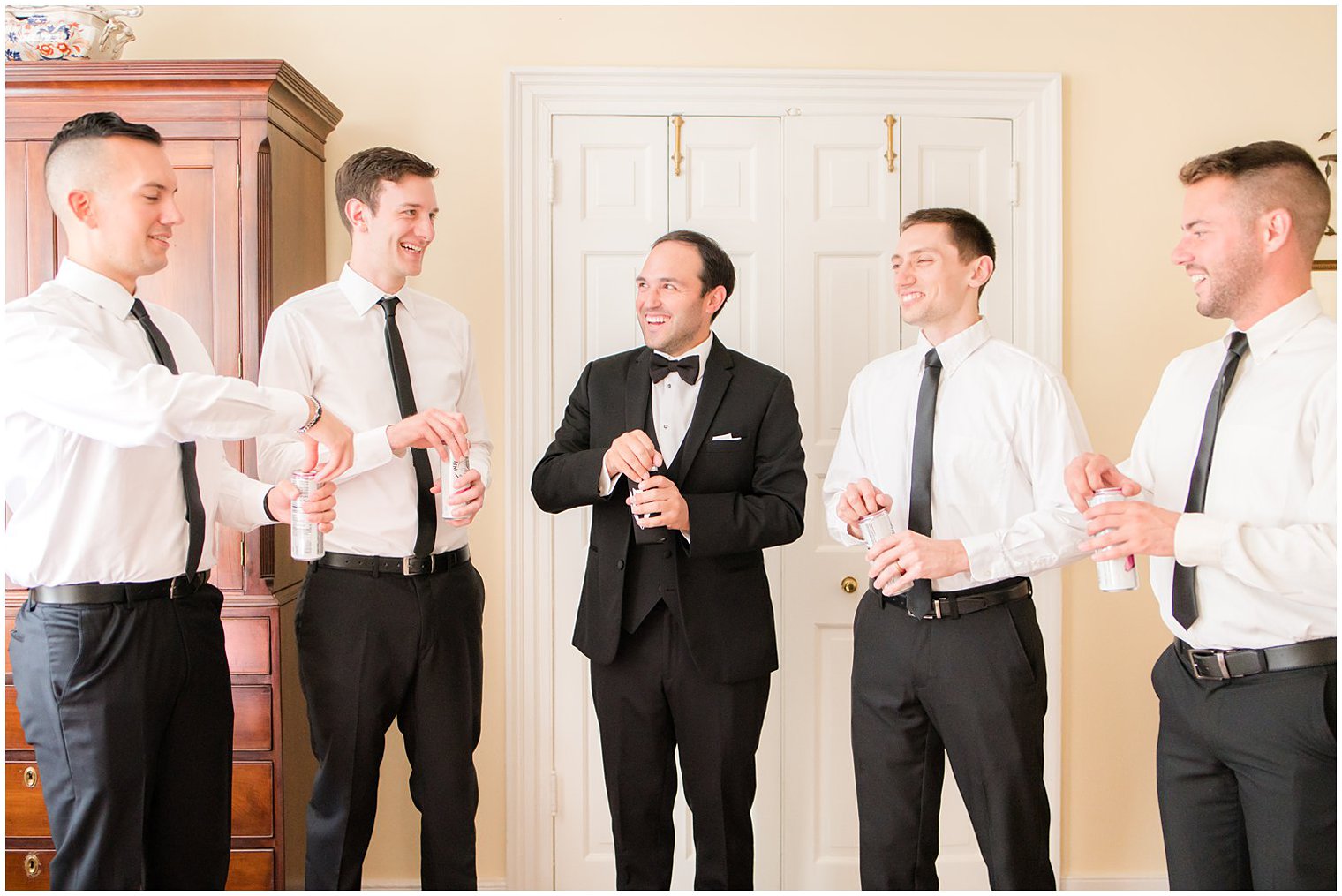 groom laughs with groomsmen preparing for wedding day
