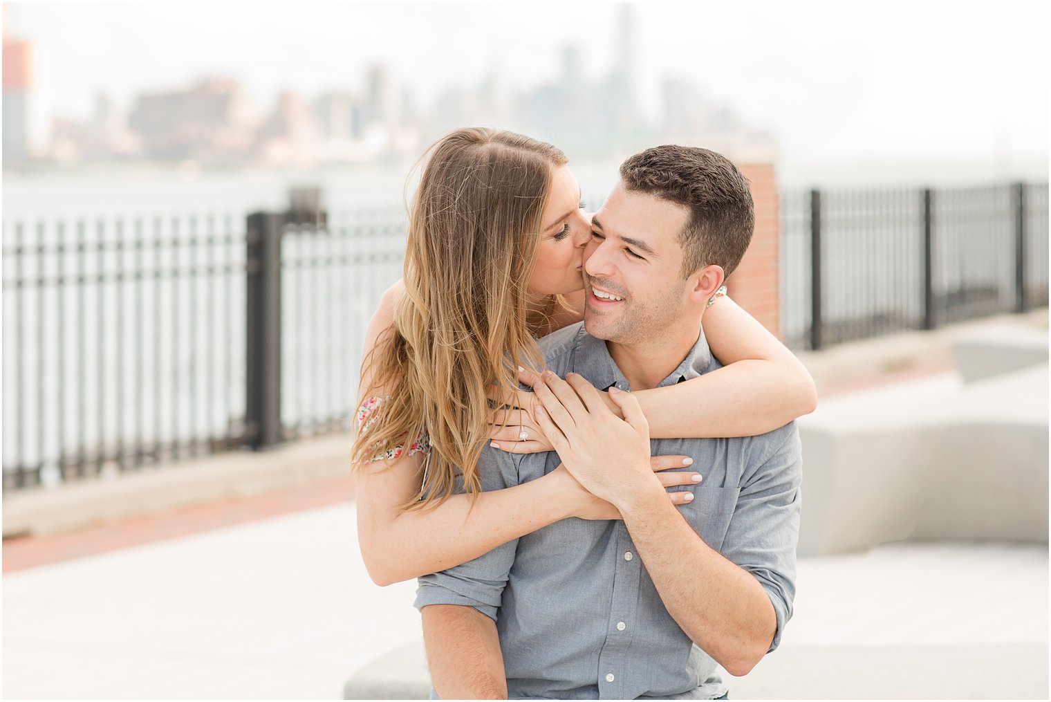 bride hugs groom from behind and kisses his cheek during NJ engagement session 