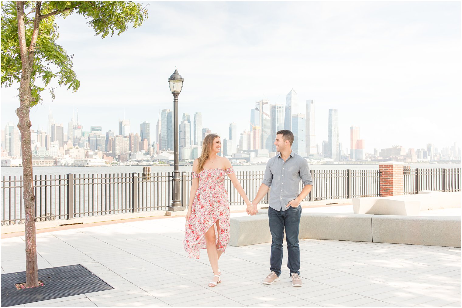 engaged couple holds hands walking through Weehawken park 