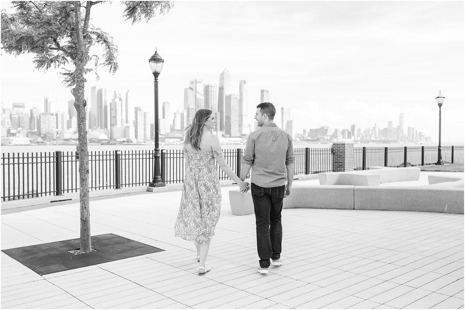 engaged couple holds hands walking through Weehawken park 