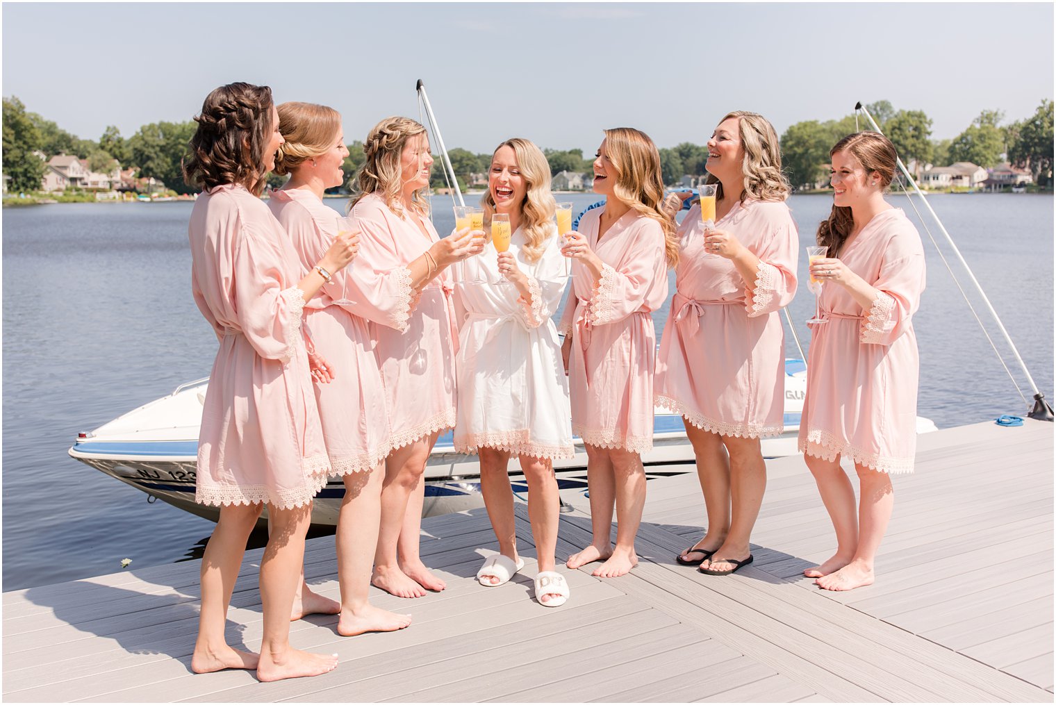 bride toasts on wedding day with bridesmaids in pink robes